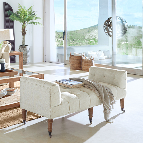 Beige gepolsterte Bank mit Holzbeinen in hellem, modernem Wohnzimmer mit grossen Fenstern