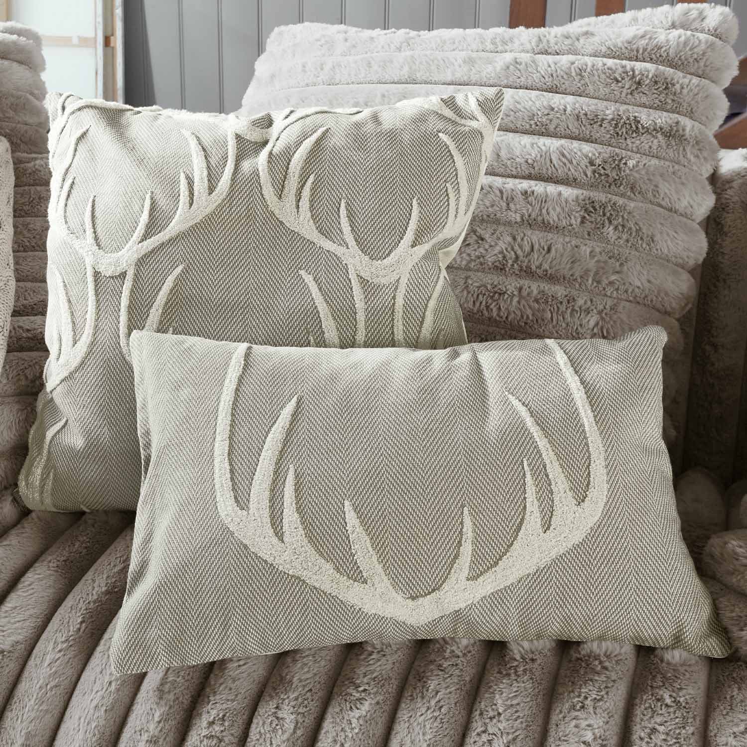 Beige Dekokissen mit Hirschgeweih-Motiv auf weichem Fellbezug, gemütliche Wohntextilien