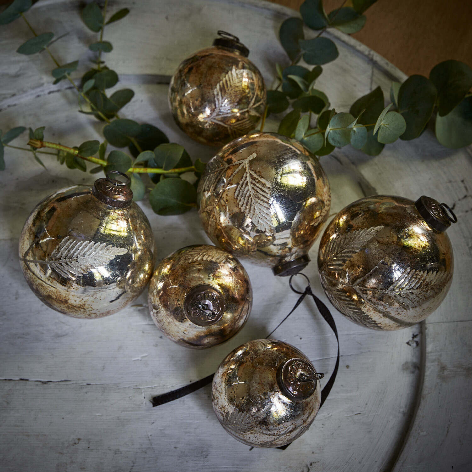 Weihnachtsschmuck 6er Set Tristan Sechs goldene Glas-Weihnachtskugeln mit Blattmotiv auf weissem Tablett mit grünen Zweigen