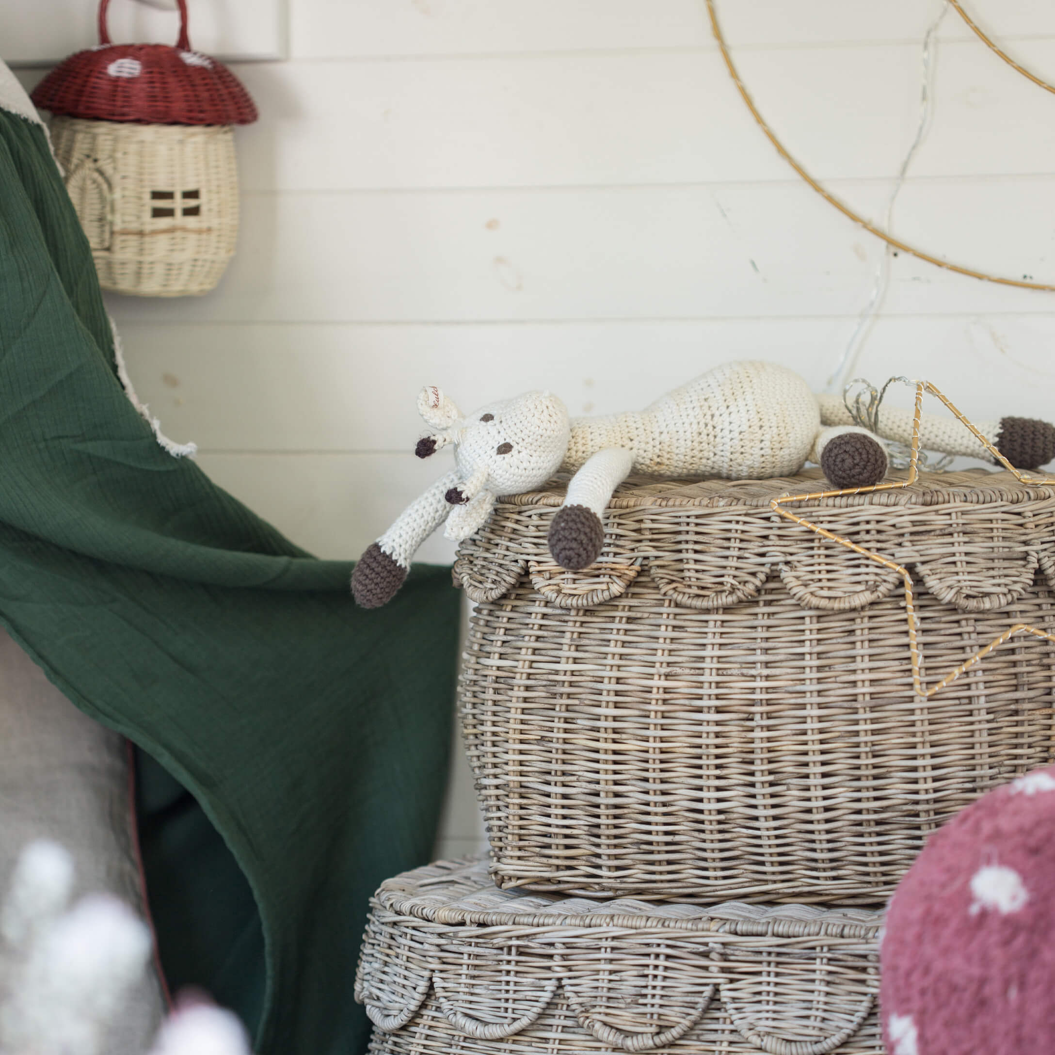 Handgehäkelte weisse und braune Giraffenpuppe auf einem dekorativen Korb aus Rattan im Boho-Stil