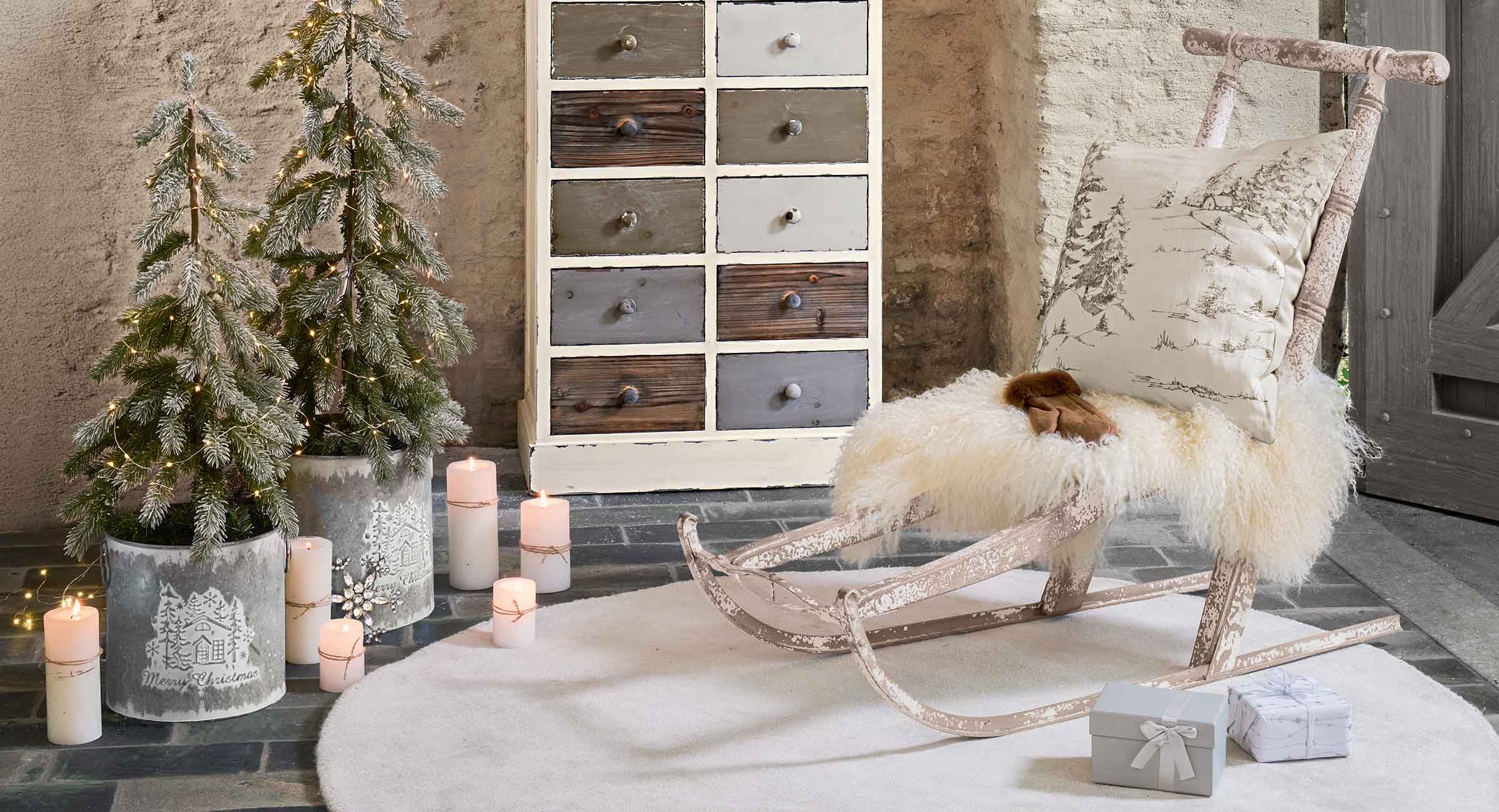 Rustikaler Holzschlitten mit weissem Fell und Kissen mit Wintermotiv in gemütlichem Raum
