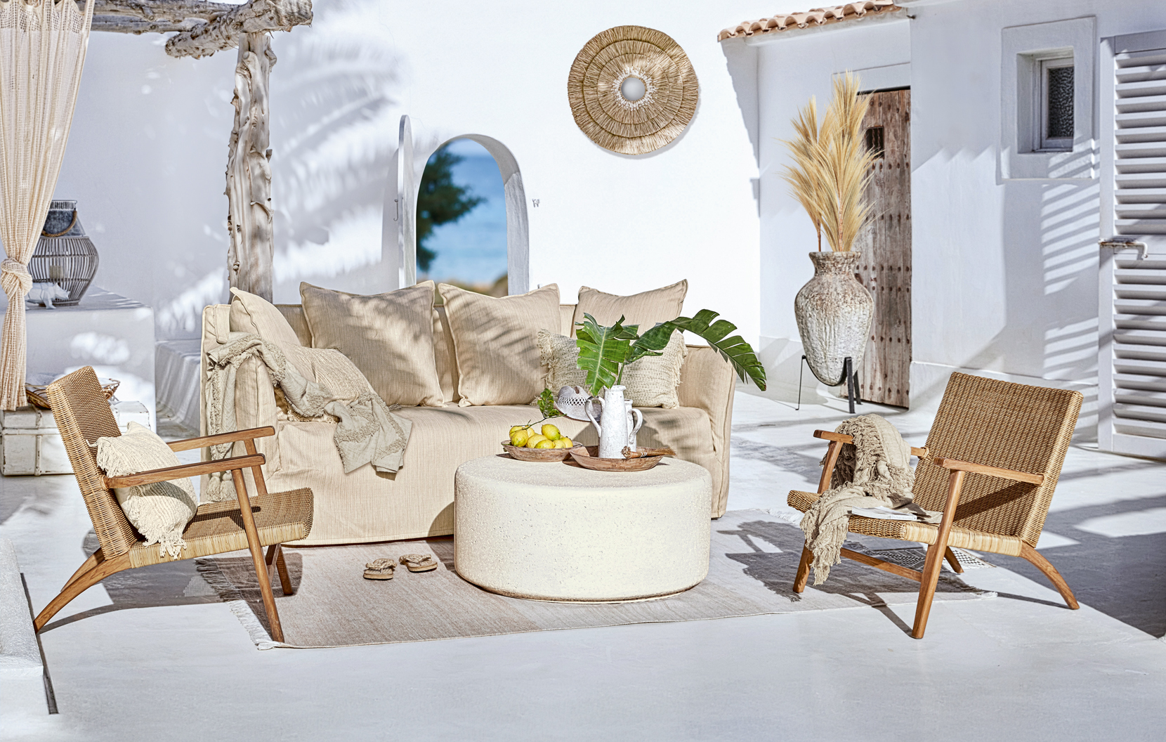 Gemütliche Boho-Gartenmöbel mit beigem Sofa und Rattanstühlen auf der sonnigen Terrasse