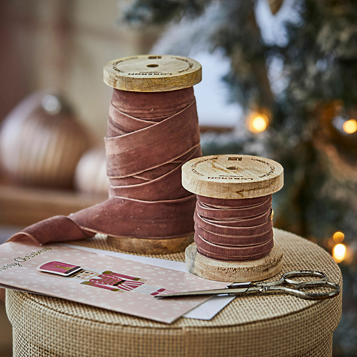 Samtband 2er Set Liandis Zwei Holzspulen mit rosa Samtband auf dem Weihnachtstisch neben einer Schere und einer Karte