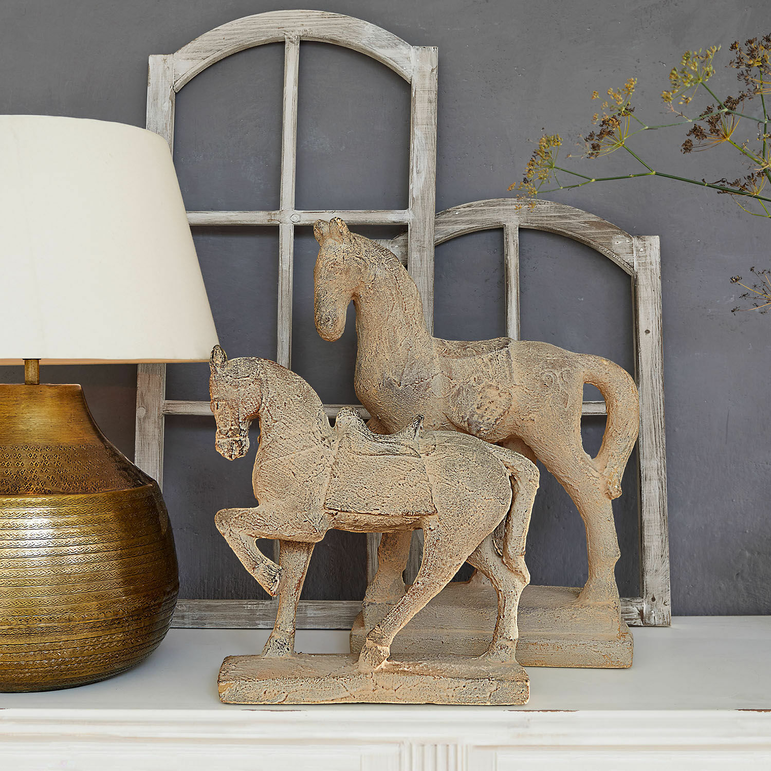 Deko-Pferd 2er Set Mirandel Dekorative Pferdefiguren aus beigem Stein auf weissem Regal mit Lampe und Holzfensterrahmen