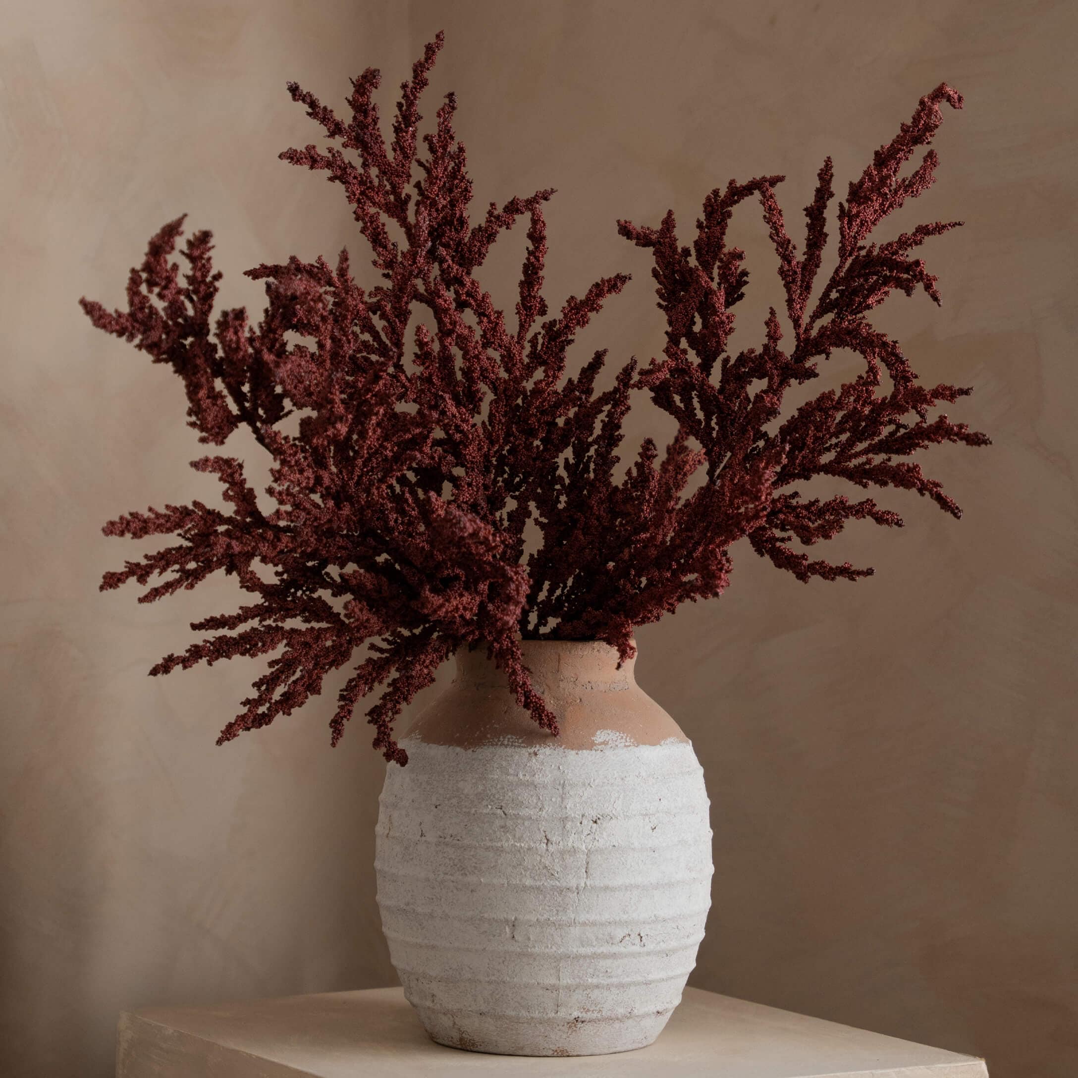Keramikvase in Weiss und Braun mit getrockneten roten Blumen als Wohnaccessoire