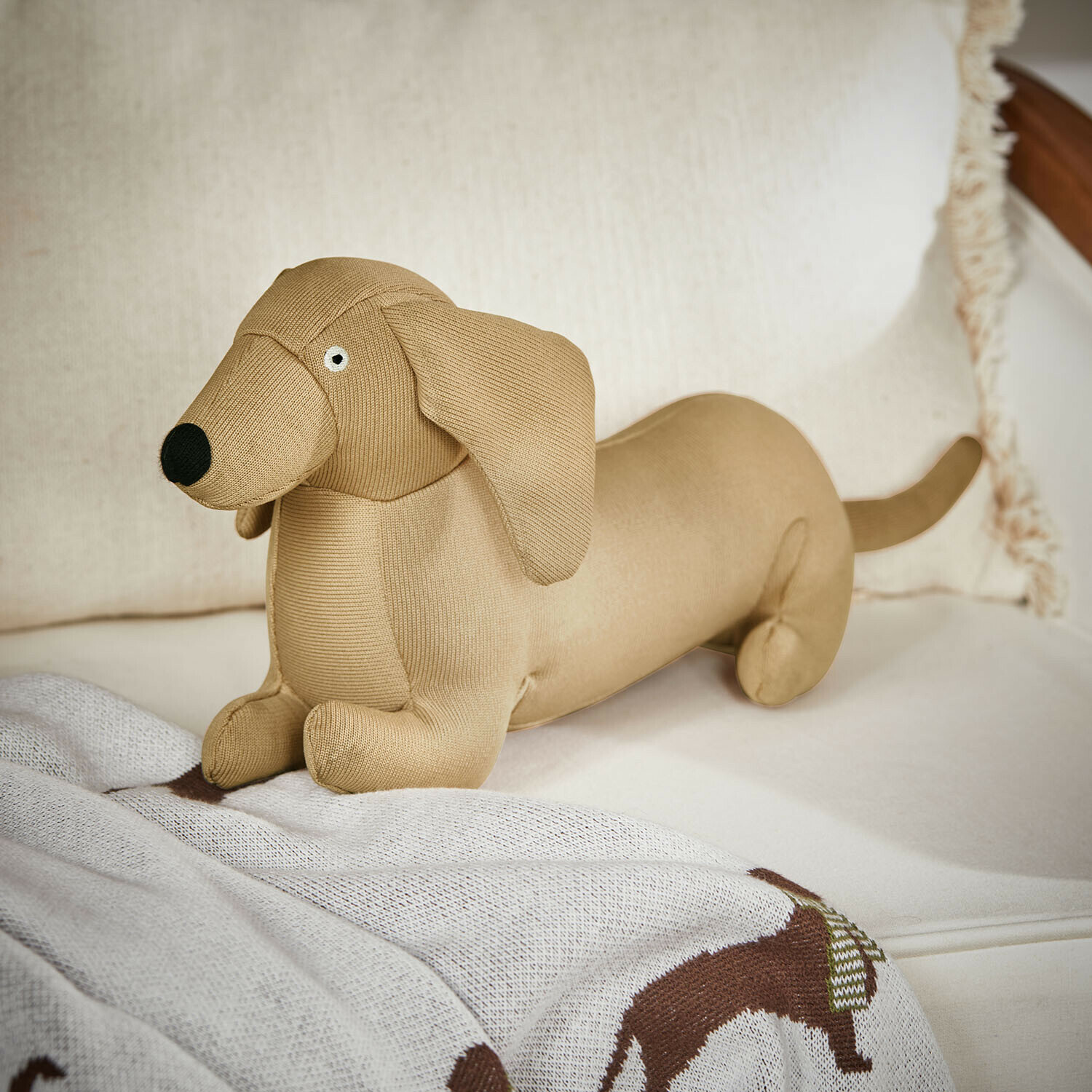 Hundespielzeug Brisette Beiger Stoff-Dackel aus weichem Material auf Sofa, dekoratives Wohnaccessoire und Kinderspielzeug