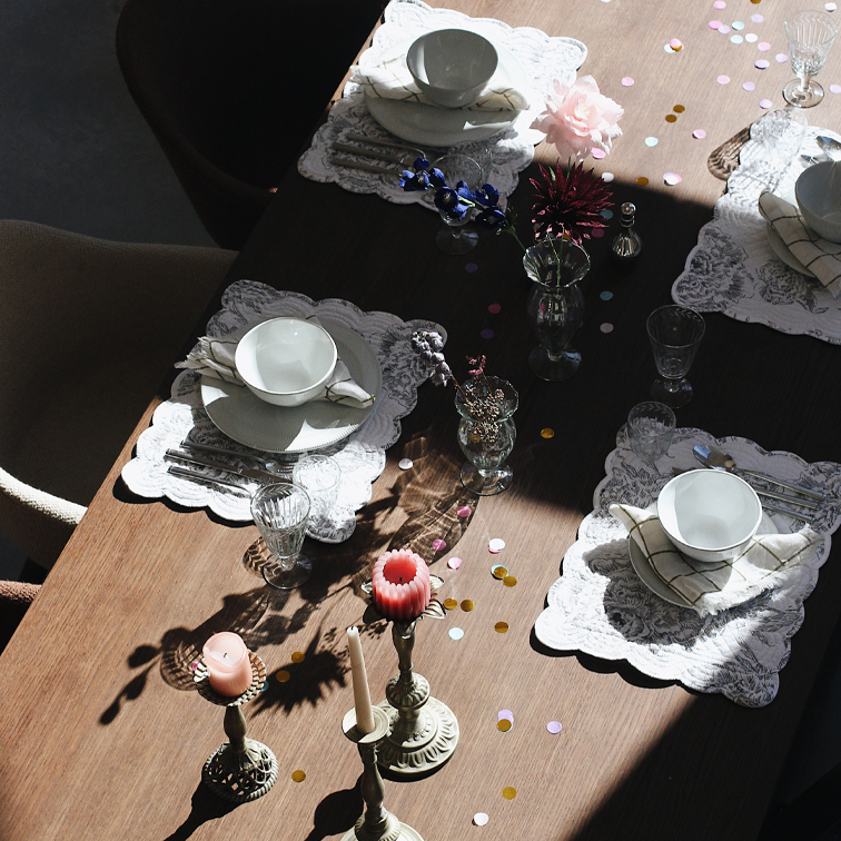 Eleganter gedeckter Tisch mit weissen Tellern, Gläsern und Kerzen auf Holzplatte