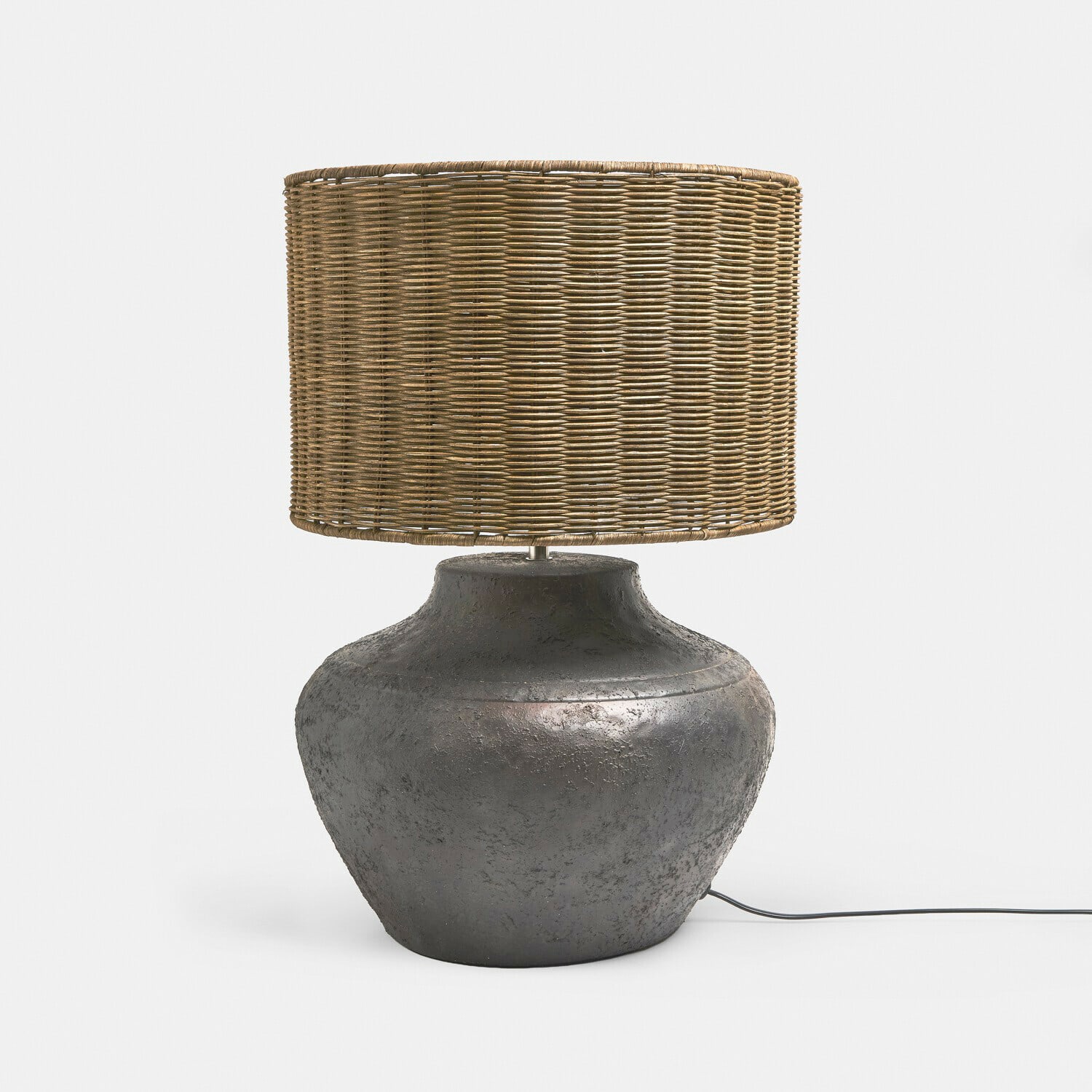 Tischlampe mit dunklem Keramikfuß und natürlichem Rattanschirm, dekorative Wohnraumbeleuchtung