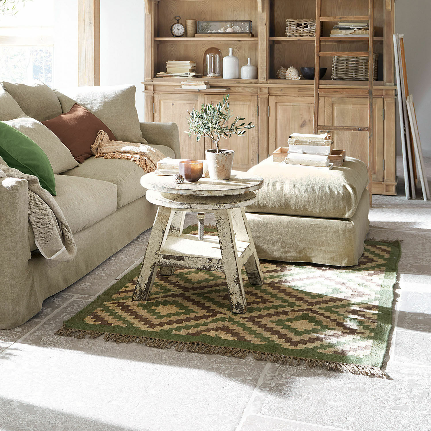 Teppich Dailies Gemütliches Wohnzimmer mit beigem Sofa, antikem Holztisch und grün-braunem Vintage-Teppich.