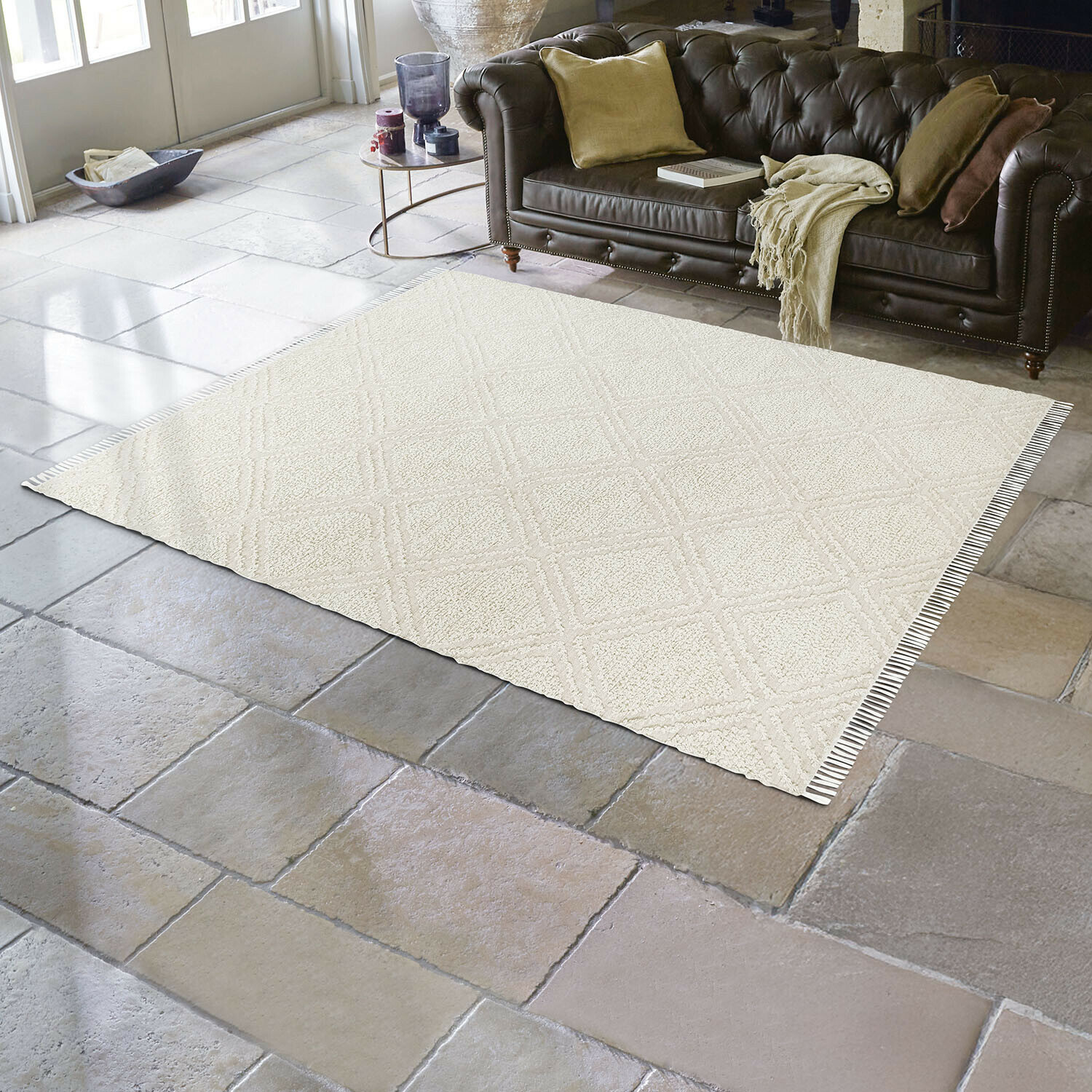 In- & Outdoor-Teppich Bruand Beigefarbener Teppich mit geometrischem Muster auf Steinboden im Wohnzimmer mit dunkelbraunem Ledersofa