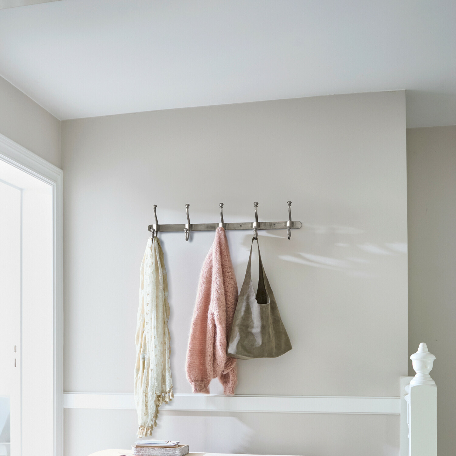 Hakenleiste Pincé Metall-Wandgarderobe mit fünf Haken, daran hängen rosa Pullover, Schal und Tasche