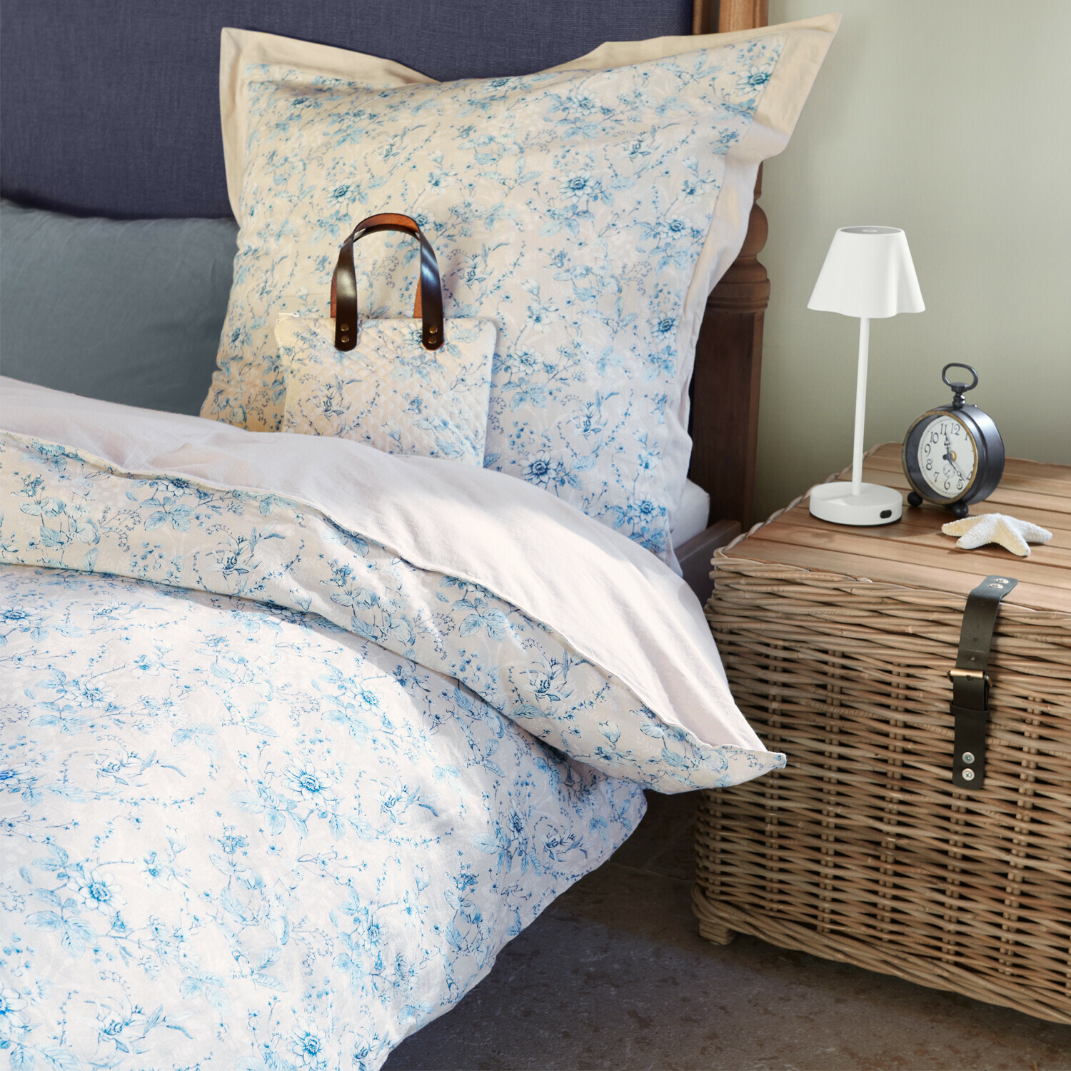 Bettwäsche Vailenne Baumwoll-Bettwäsche mit hellblauem Blumenmuster auf Bett neben Korbschrank und Lampe