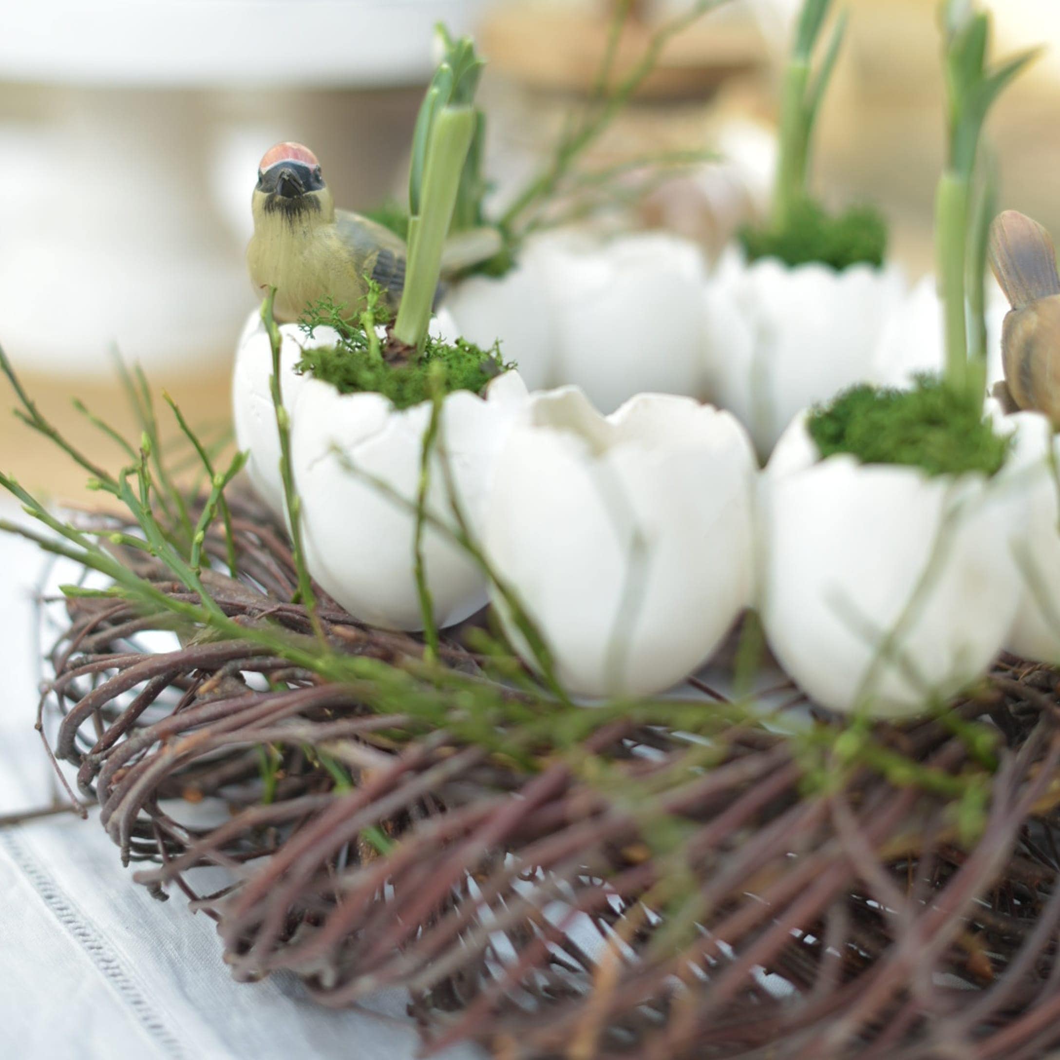 Dekorativer Kranz mit weissen Keramikeiern, grünem Moos und Vogel-Figuren für Osterdekoration