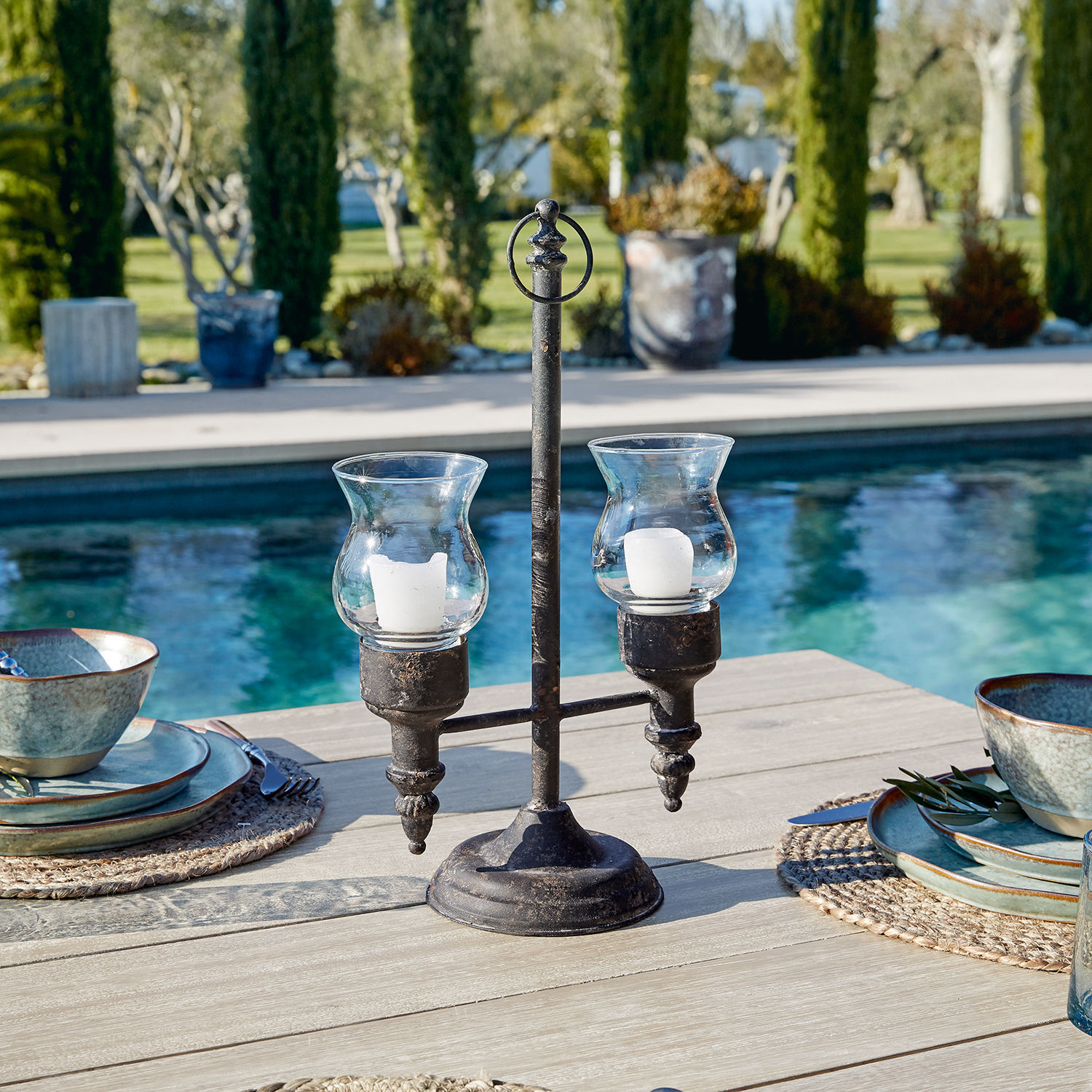 Windlicht Oiusseau Metall-Kerzenhalter mit zwei Glashüllen für weisse Kerzen auf Gartentisch am Pool