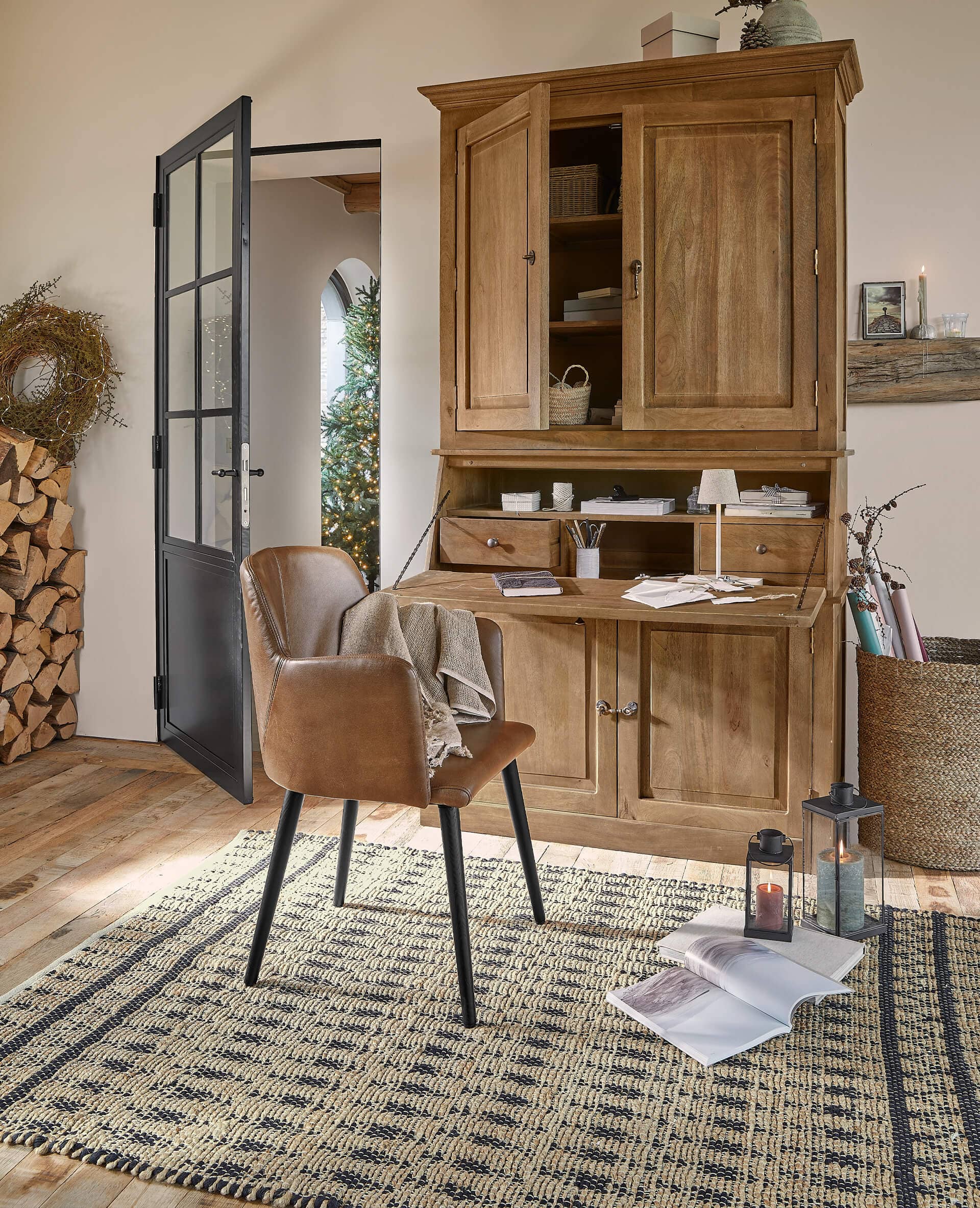 Holzschrank mit offenem Klapptisch und braunem Lederstuhl auf Teppich in gemütlichem Raum