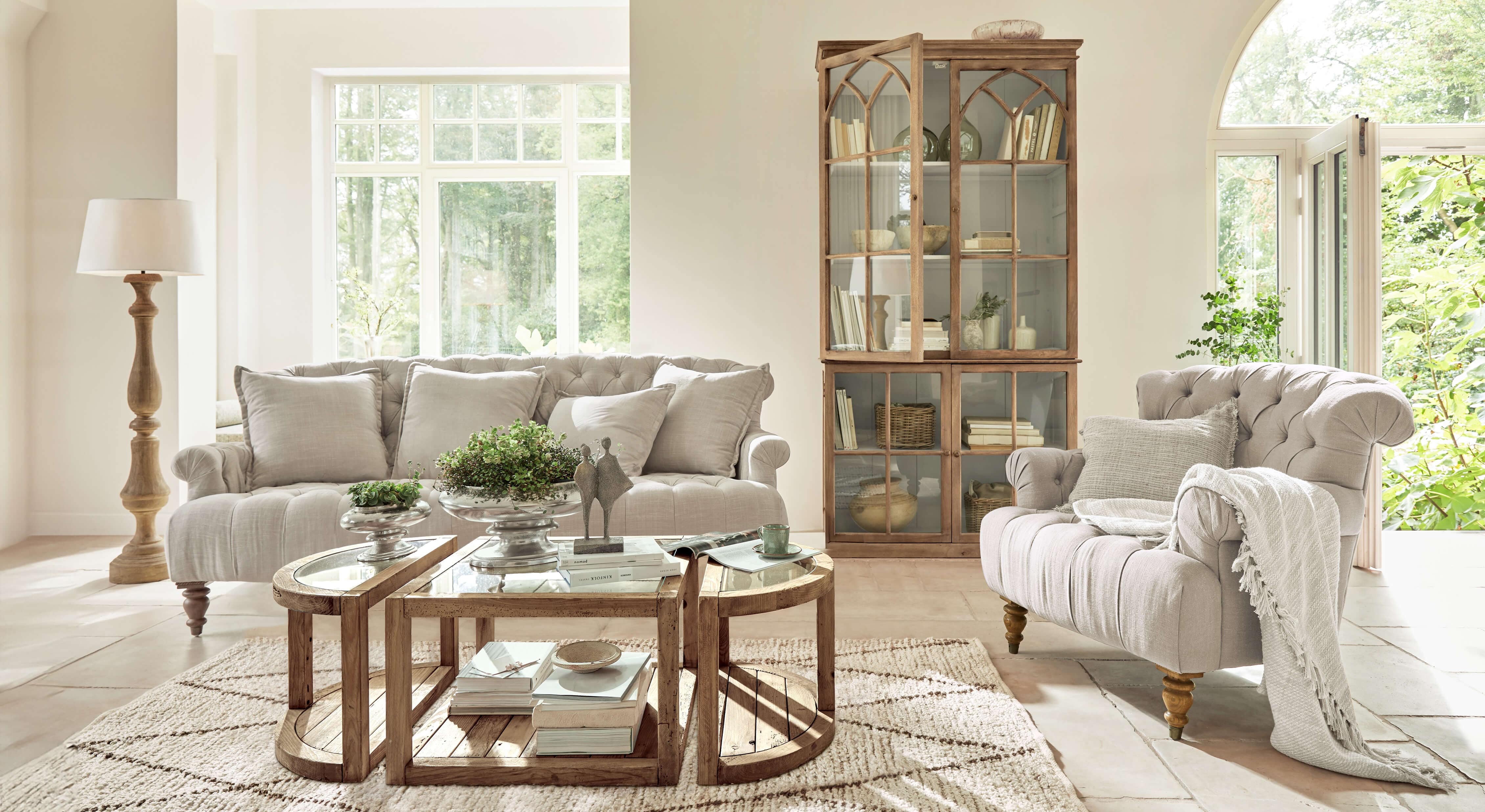 Gemütliches Wohnzimmer mit beigem Stoffsofa und Sessel, Holzmöbeln und rustikalem Couchtisch