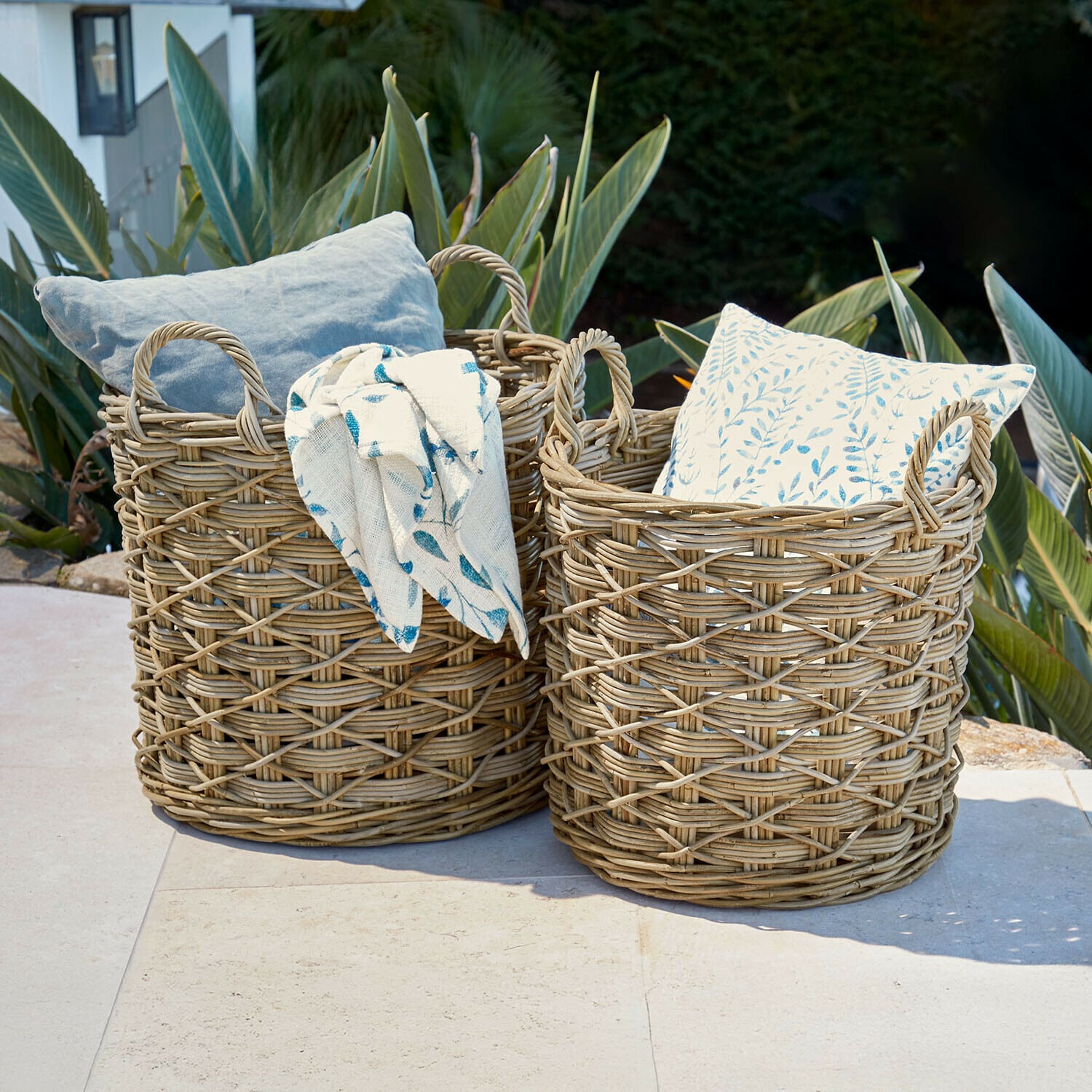 Zwei naturfarbene Weidenkörbe mit Kissen und Decke, Gartendekoration im Freien