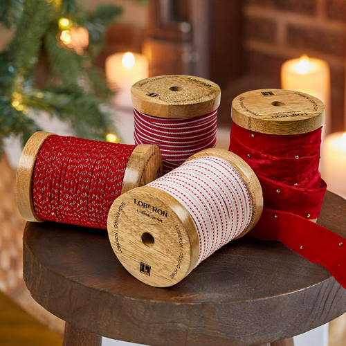 Vier Holzspulen mit roten und weissen Dekobändern für festliche Weihnachtsdekorationen
