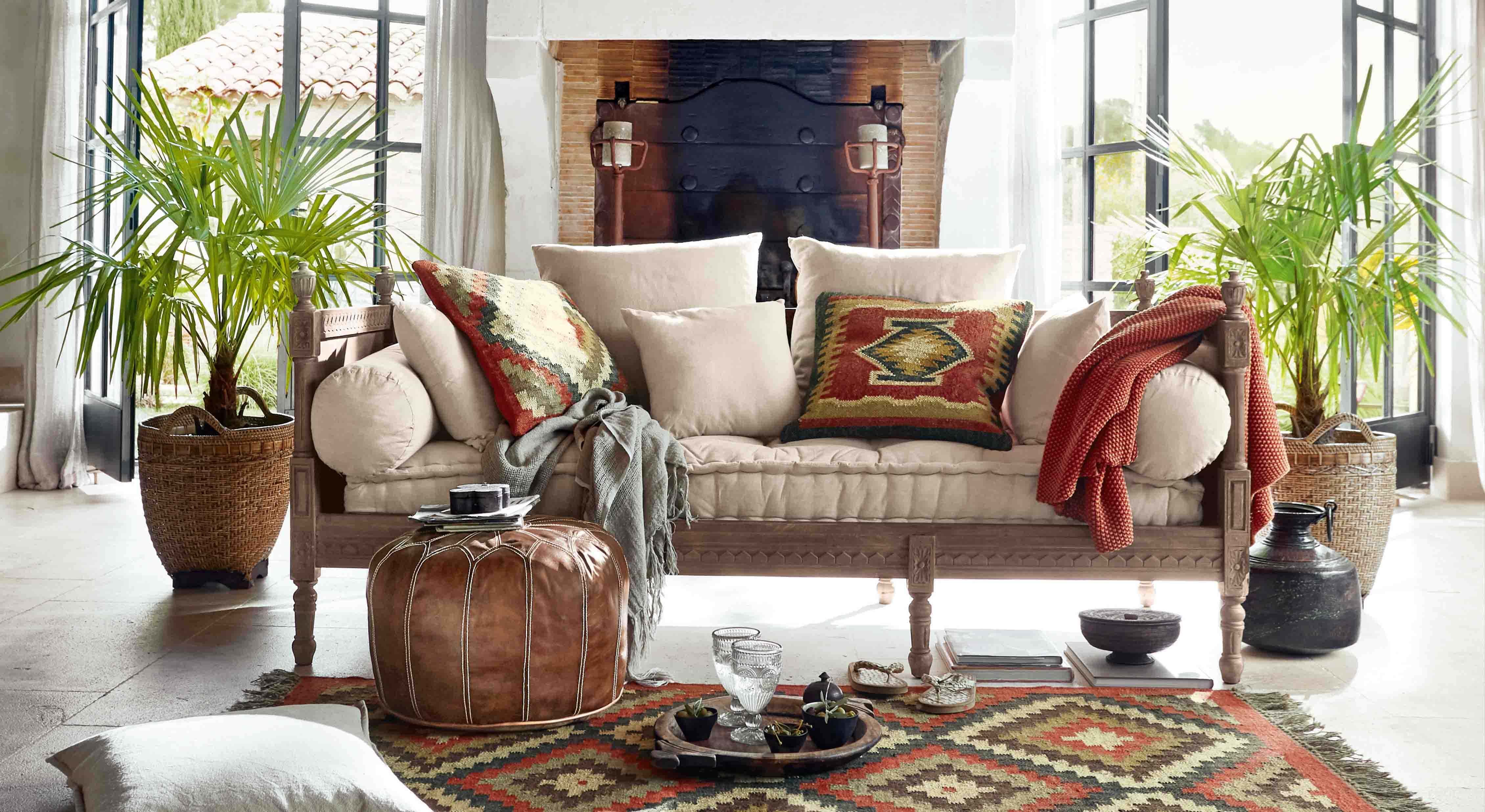 Sofa mit hellbeigem Bezug und Holzrahmen, bunte Kissen und Boho-Decke in hellem Wohnzimmer
