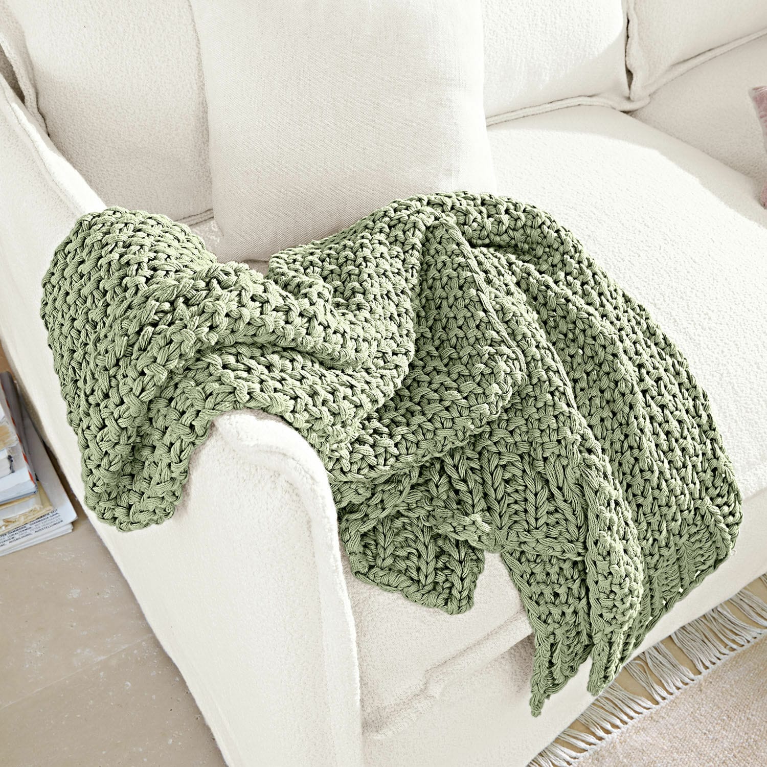 Plaid Plixoren Weiche, grün grob gestrickte Decke auf weissem Sofa, gemütliche Wohnraumdekoration