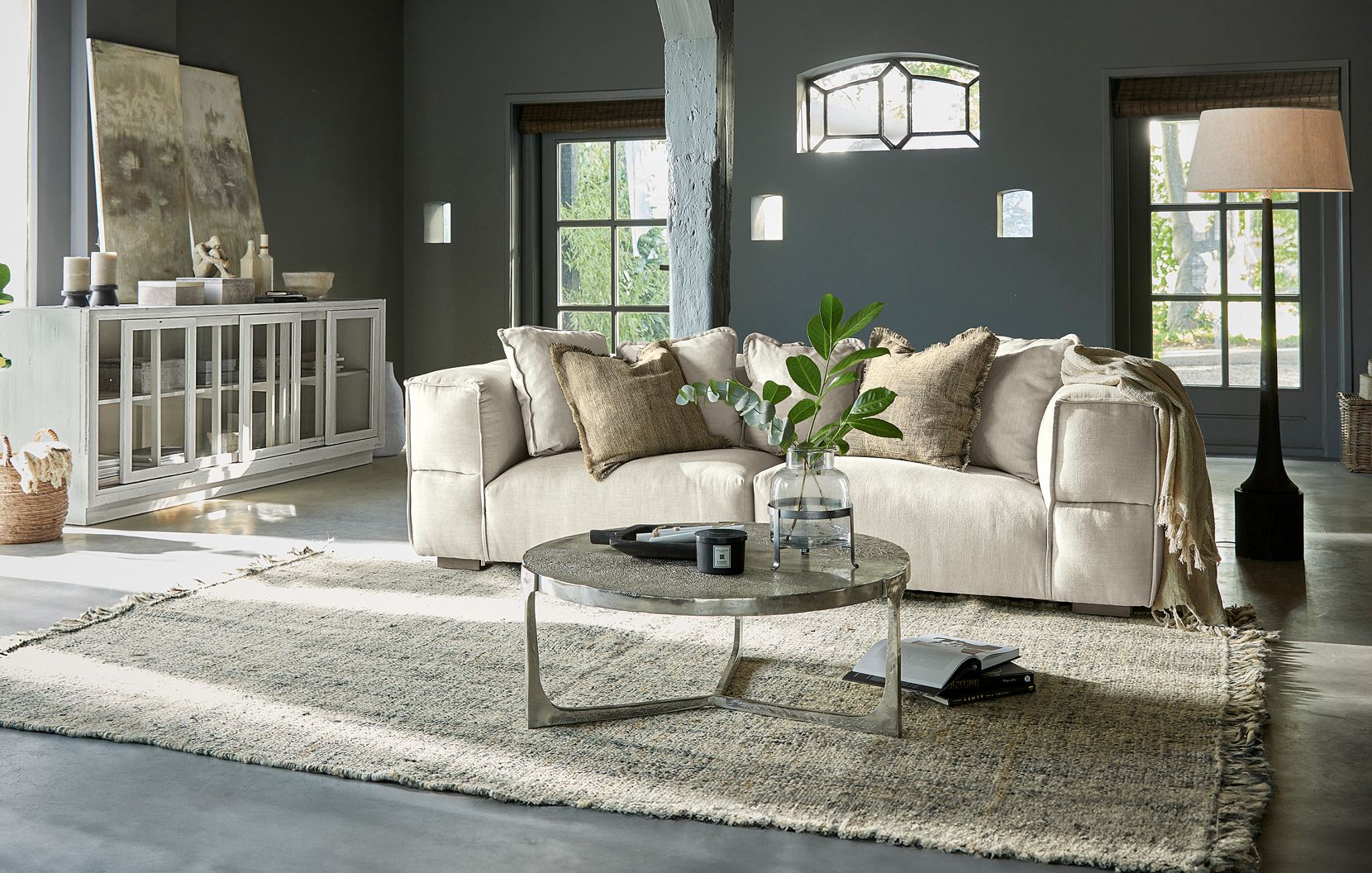 Geräumiges Wohnzimmer mit beigem Stoffsofa, Metall-Couchtisch und Teppich im Industriedesign