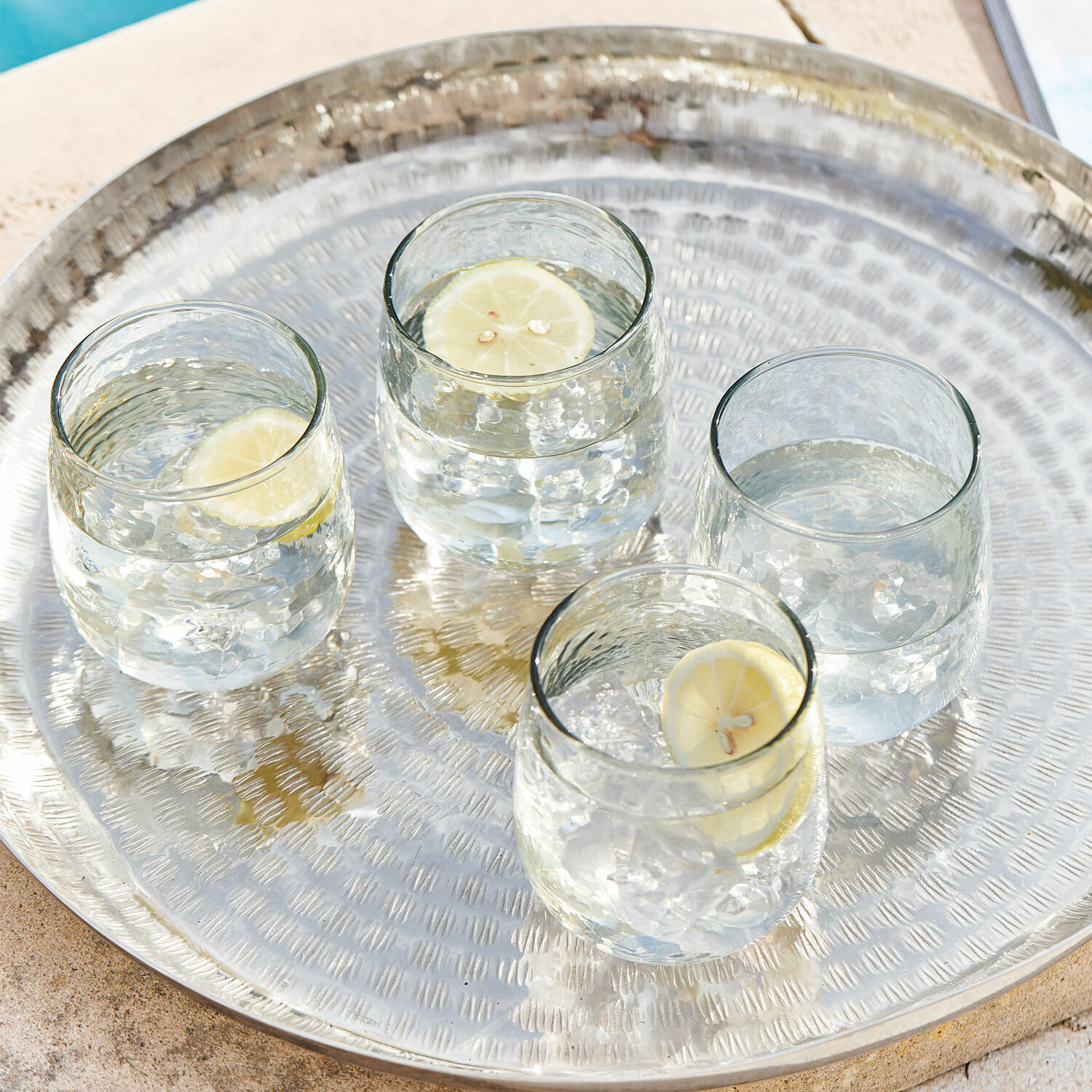 Glas 4er Set Valters Metalltablett mit vier Gläsern Wasser und Zitronenscheiben am Poolrand
