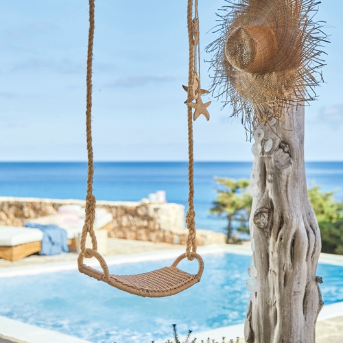 Geflochtene Seilschaukel vor Pool und Meerblick, sommerliche Gartendekoration