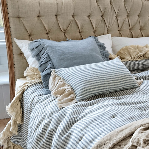 Beige und blaue Leinenkissen mit gestreifter Leinenbettdecke auf gepolstertem Kopfteil