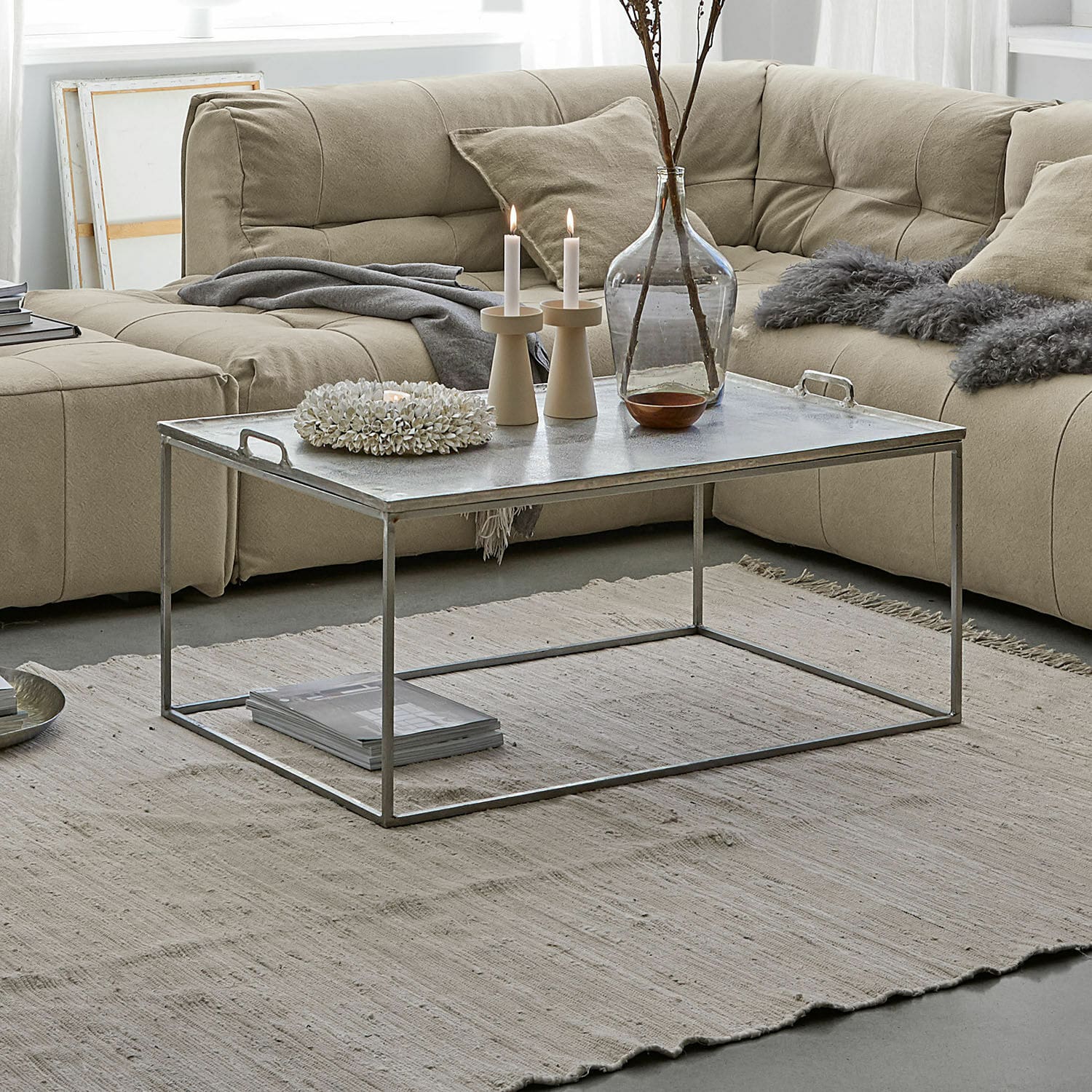 Moderner Couchtisch mit Metallgestell und silberner Tischplatte auf beigem Teppich im Wohnzimmer