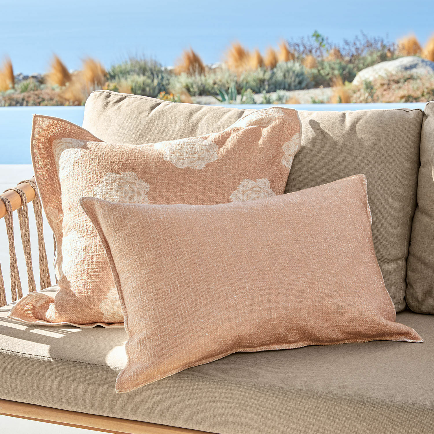 Kissenhülle 2er Set Belvienne Beige Leinen-Dekokissen auf beigem Sofa im Freien mit Blick auf den Garten und den Himmel