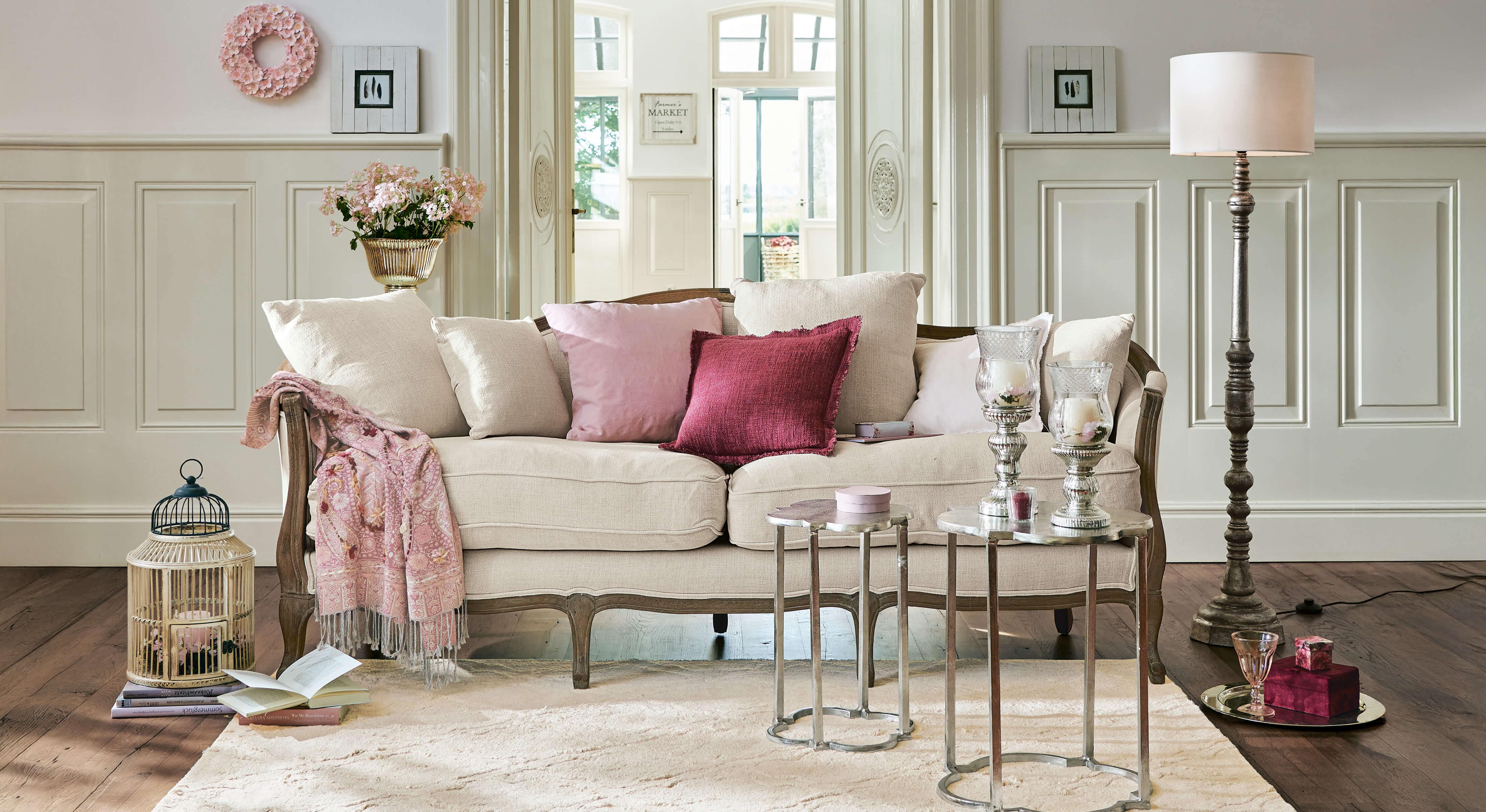 Beiges Sofa mit Holzrahmen und rosa Kissen in elegantem Wohnzimmer mit Dekorationen
