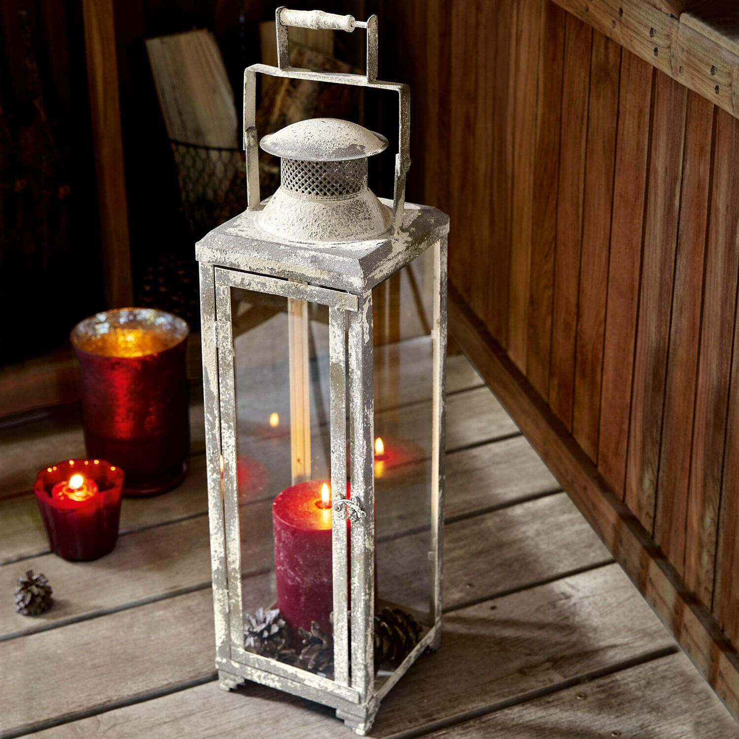 Laterne Isodore Metalllaterne im Vintage-Stil mit weisser Patina und roter Kerze auf Holzboden