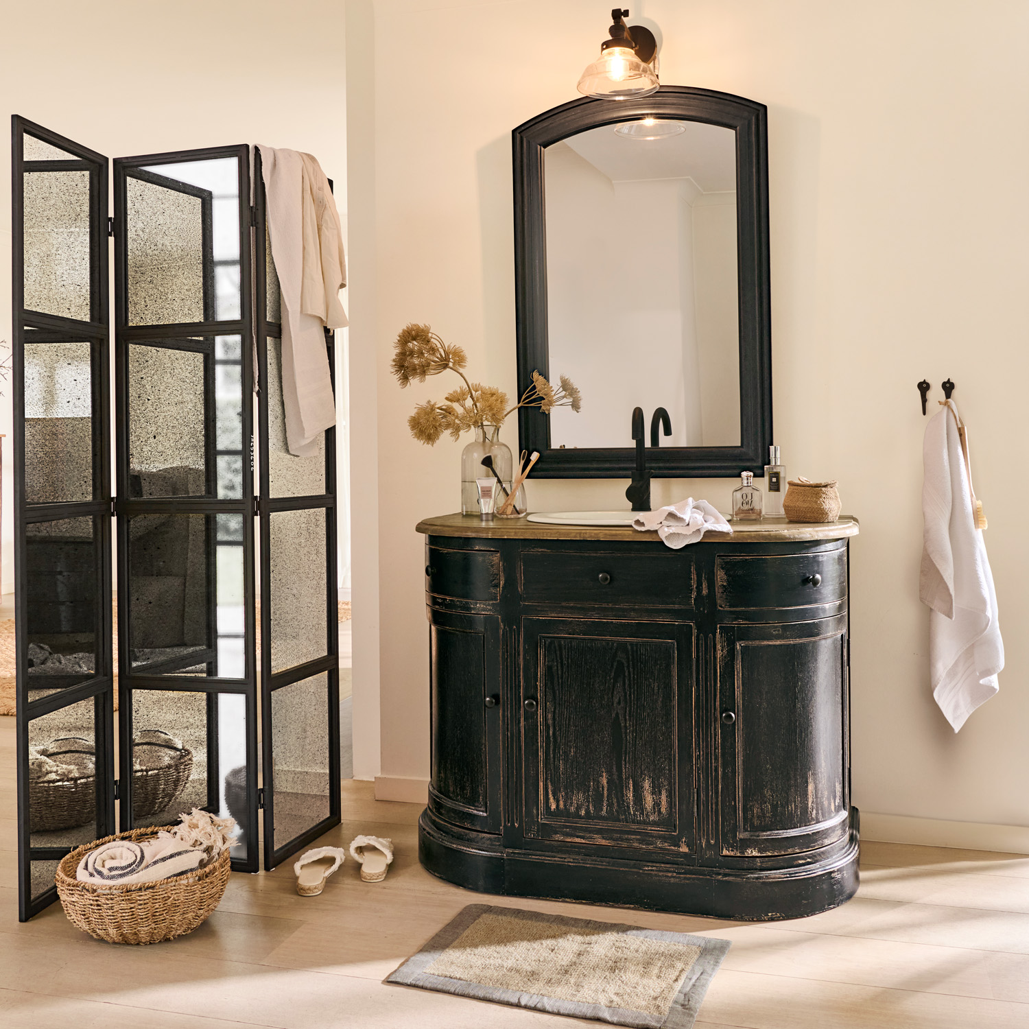 Schwarzer Holz-Badezimmerschrank mit Spiegel und schwarzem Wasserhahn, natürliche Accessoires und Paravent