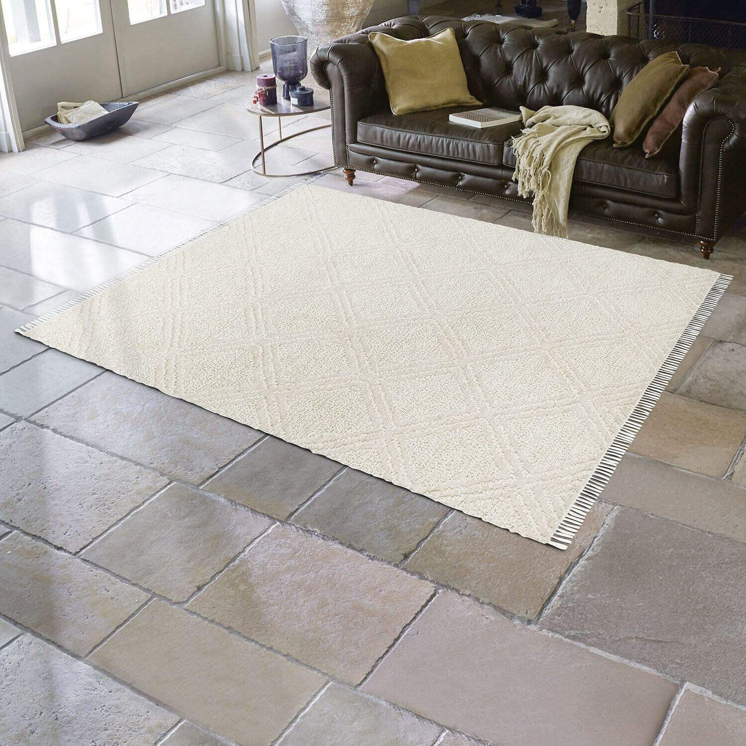 In- & Outdoor-Teppich Bruand Beiger Teppich mit geometrischem Muster auf Steinboden im Wohnzimmer mit braunem Ledersofa
