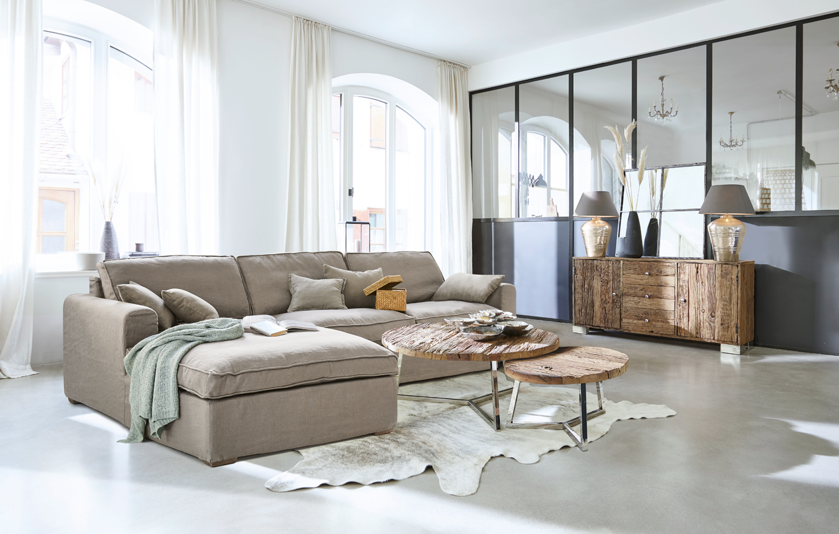 Helles Wohnzimmer mit beigem Stoffsofa und rustikalen Holztischen im modernen Industriedesign