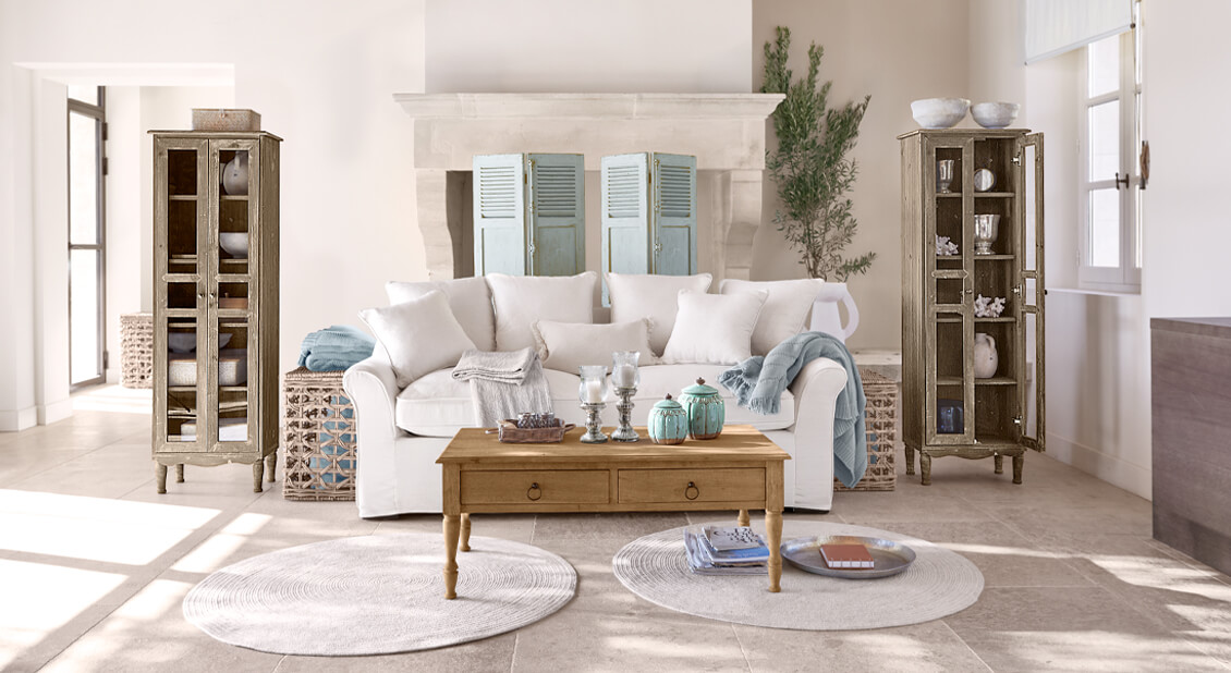 Gemütliches weisses Baumwollsofa im maritimen Stil mit Holztisch und Dekorationen im hellen Wohnzimmer