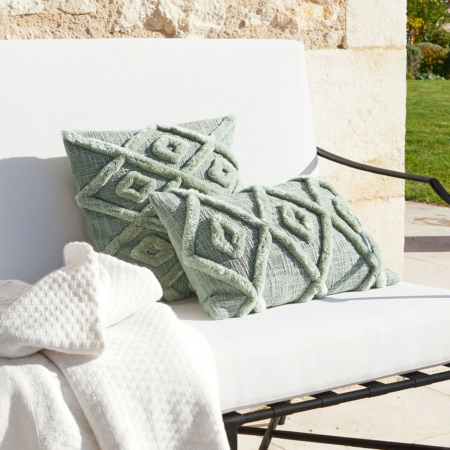 Mintgrüne Dekokissen mit geometrischem Muster auf weissem Sofa mit Decke, Wohntextilien