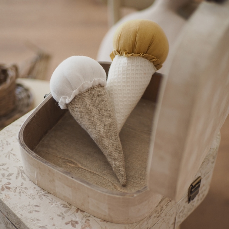 Zwei dekorative Stoff-Eistüten in Weiss und Senfgelb in einer Holzkiste auf dem Tisch