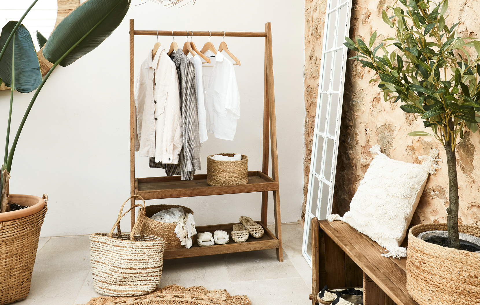Holz-Kleiderständer mit hellen Hemden und Weidenkorb im Boho-Wohnstil