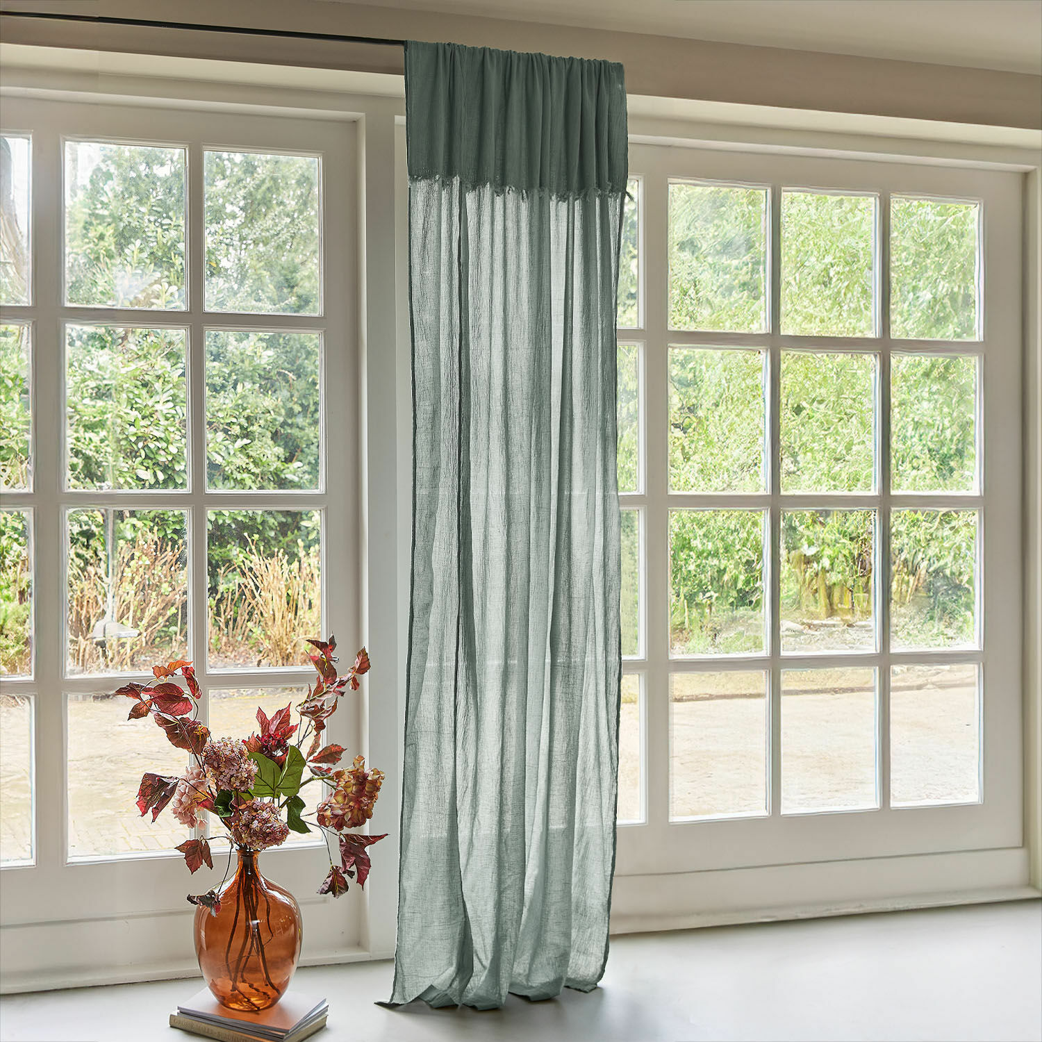 Gardine Dovinel Transparenter grüner Leinenvorhang am grossen Fenster mit Gartensicht und Vase mit Blumen