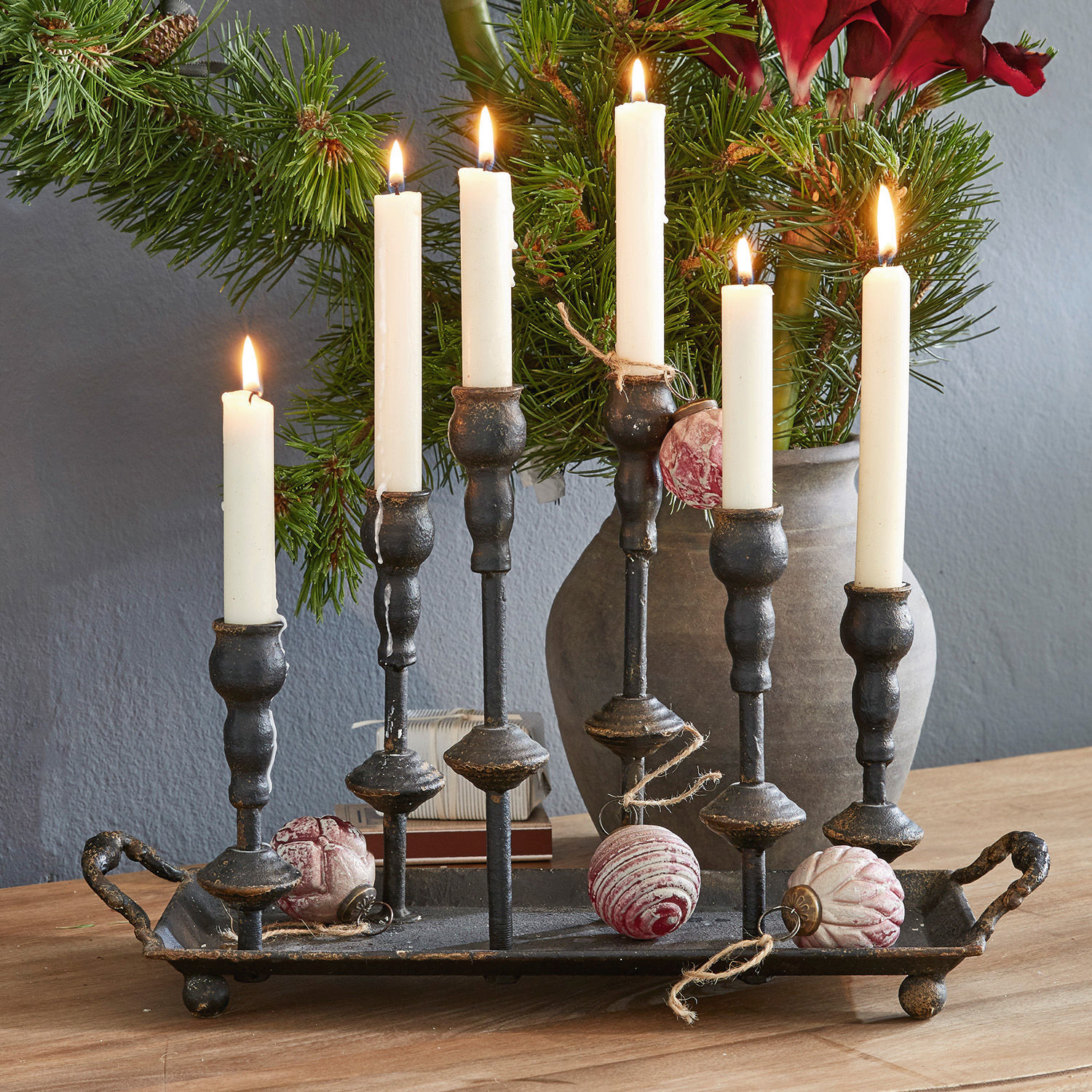 Kerzenständer Aisa Schwarzer Metall-Kerzenhalter mit sechs weißen Kerzen und Weihnachtskugeln auf Holztisch