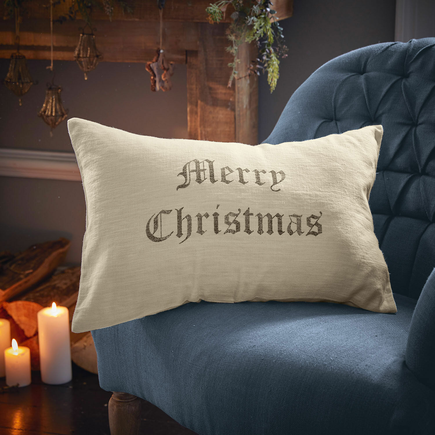 Kissenhülle Merry Christmas Beiges Leinenkissen mit Schriftzug Merry Christmas auf blauem Sessel, weihnachtliche Dekoration