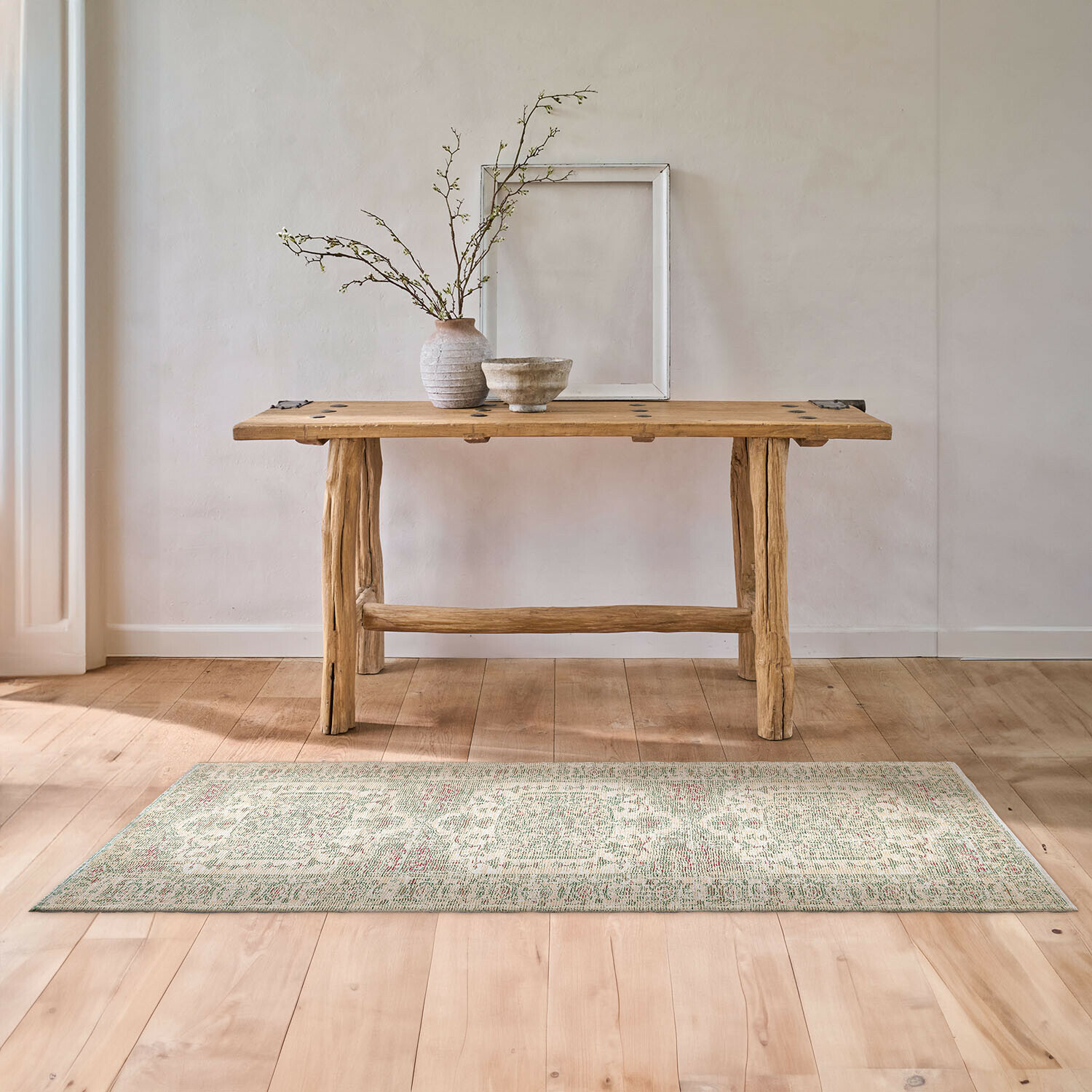 Läufer Taranise Heller Vintage-Teppich auf Holzboden vor rustikalem Holztisch mit Vasen und Bilderrahmen