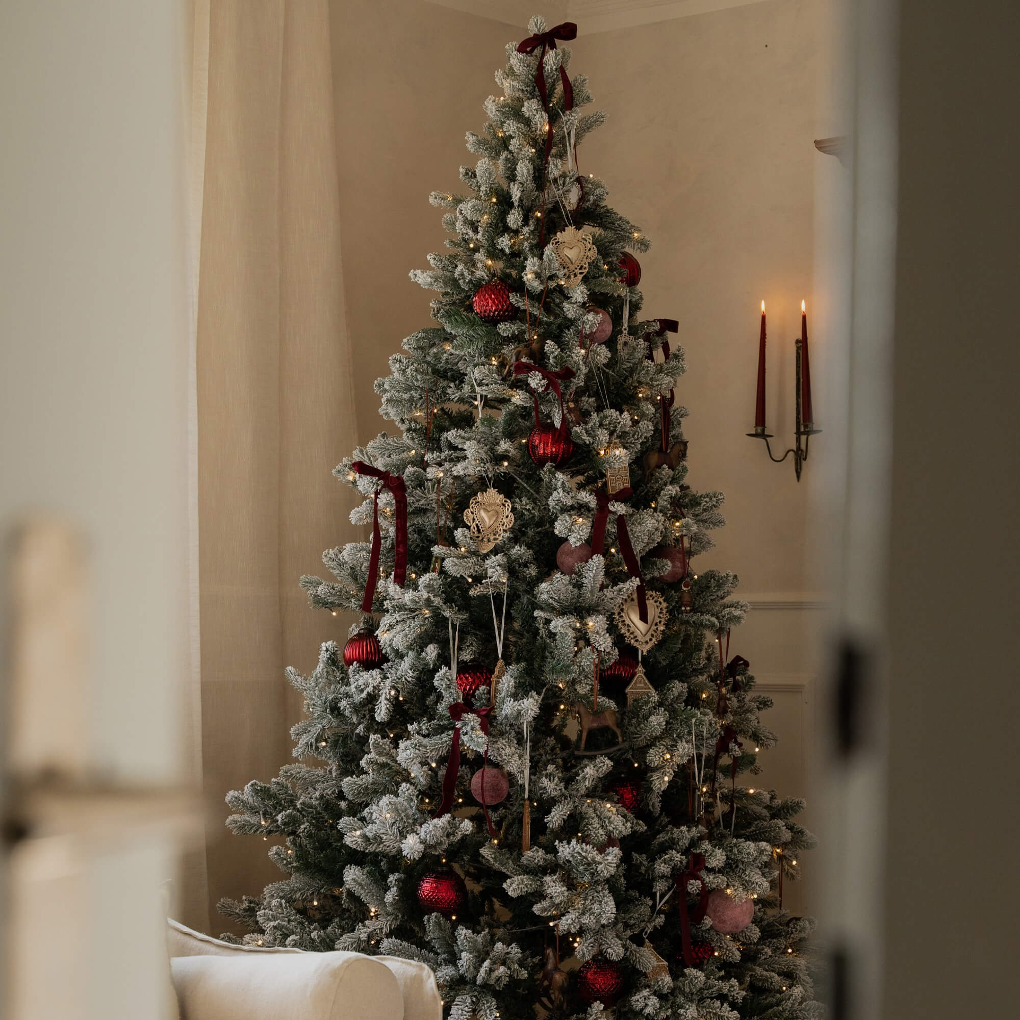 Künstlicher Weihnachtsbaum mit weissem Schneeeffekt und roten Kugeln, festliche Wohnraumdekoration