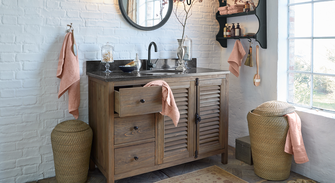Badezimmer mit Holzschrank, schwarzer Arbeitsplatte und terrakottafarbenen Handtüchern, natürliche Dekoration