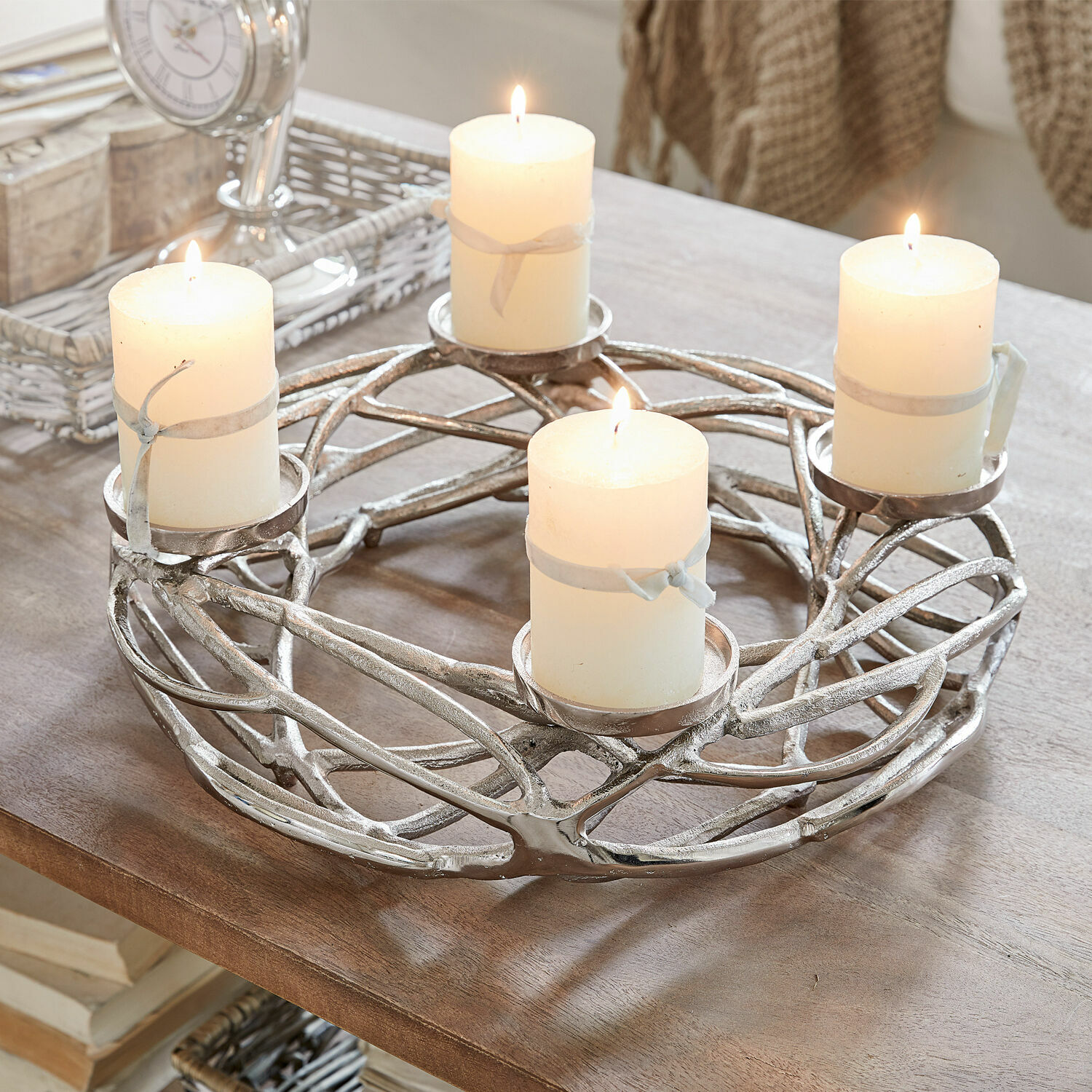 Silberner Metall-Kerzenhalter mit vier weißen brennenden Kerzen auf Holztisch, Wohnaccessoire