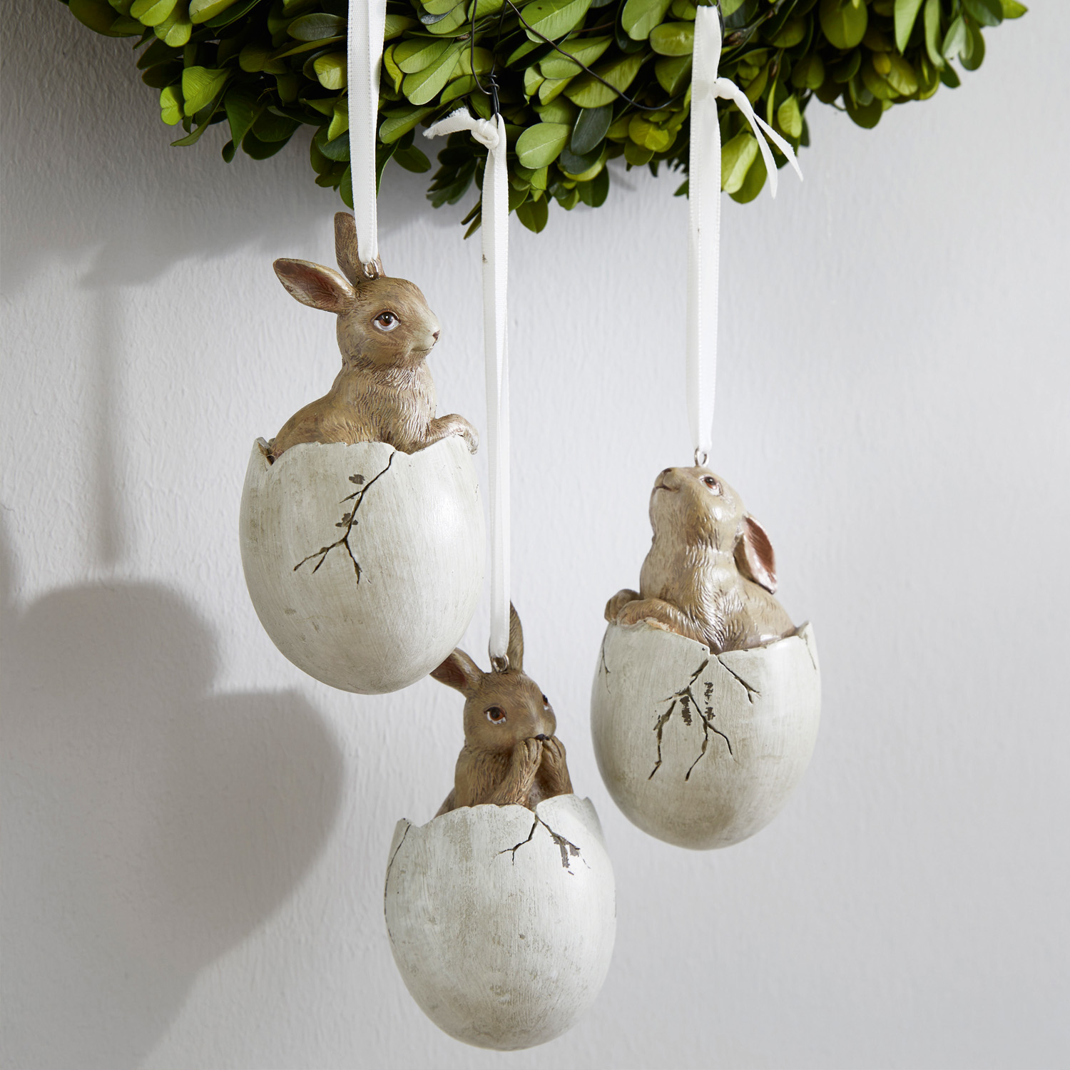 Drei hängende Osterdekorationen mit Hasen in weissen Eierschalen aus Kunstmaterial