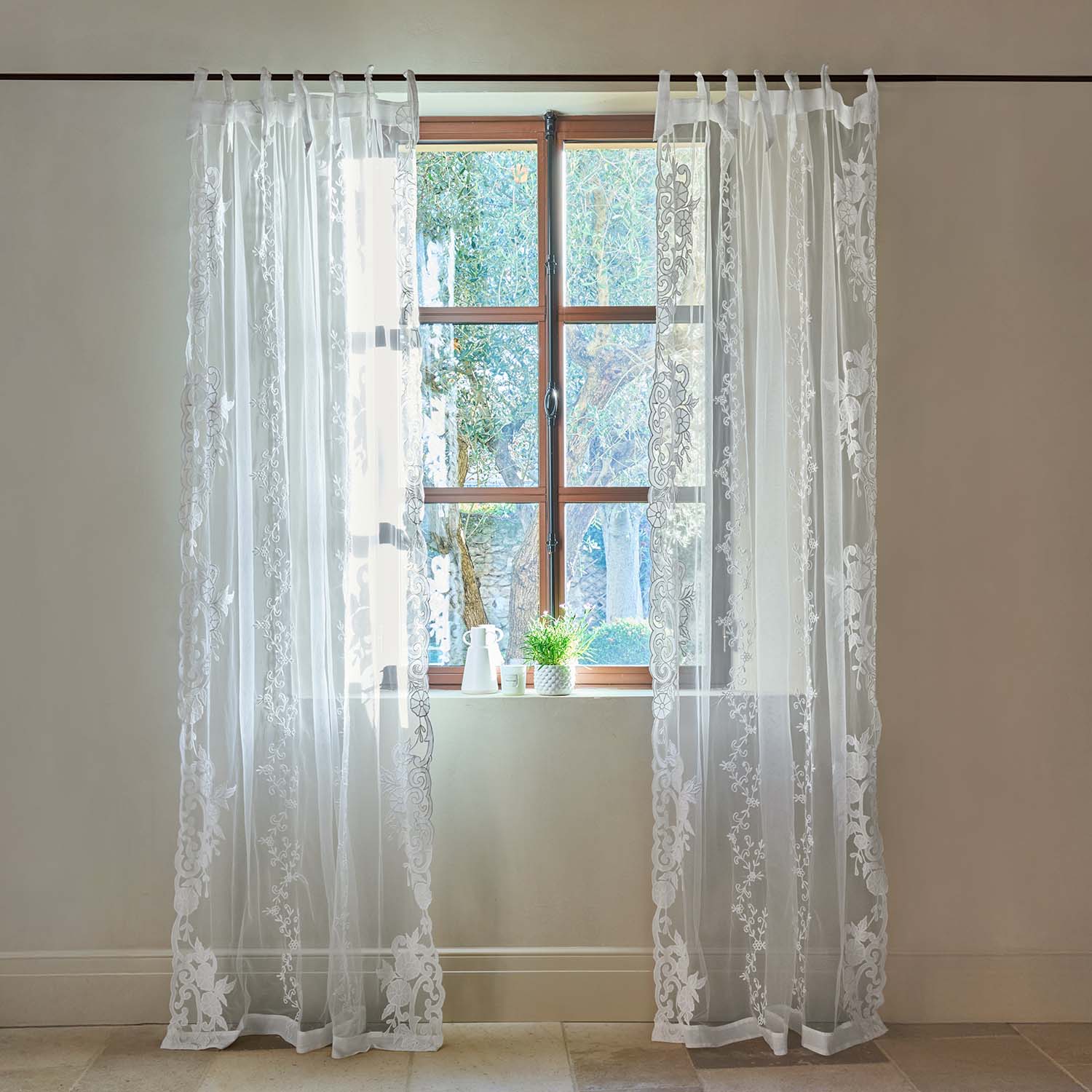 Transparente weisse Gardinen mit besticktem Blumenmuster an Holzfenster