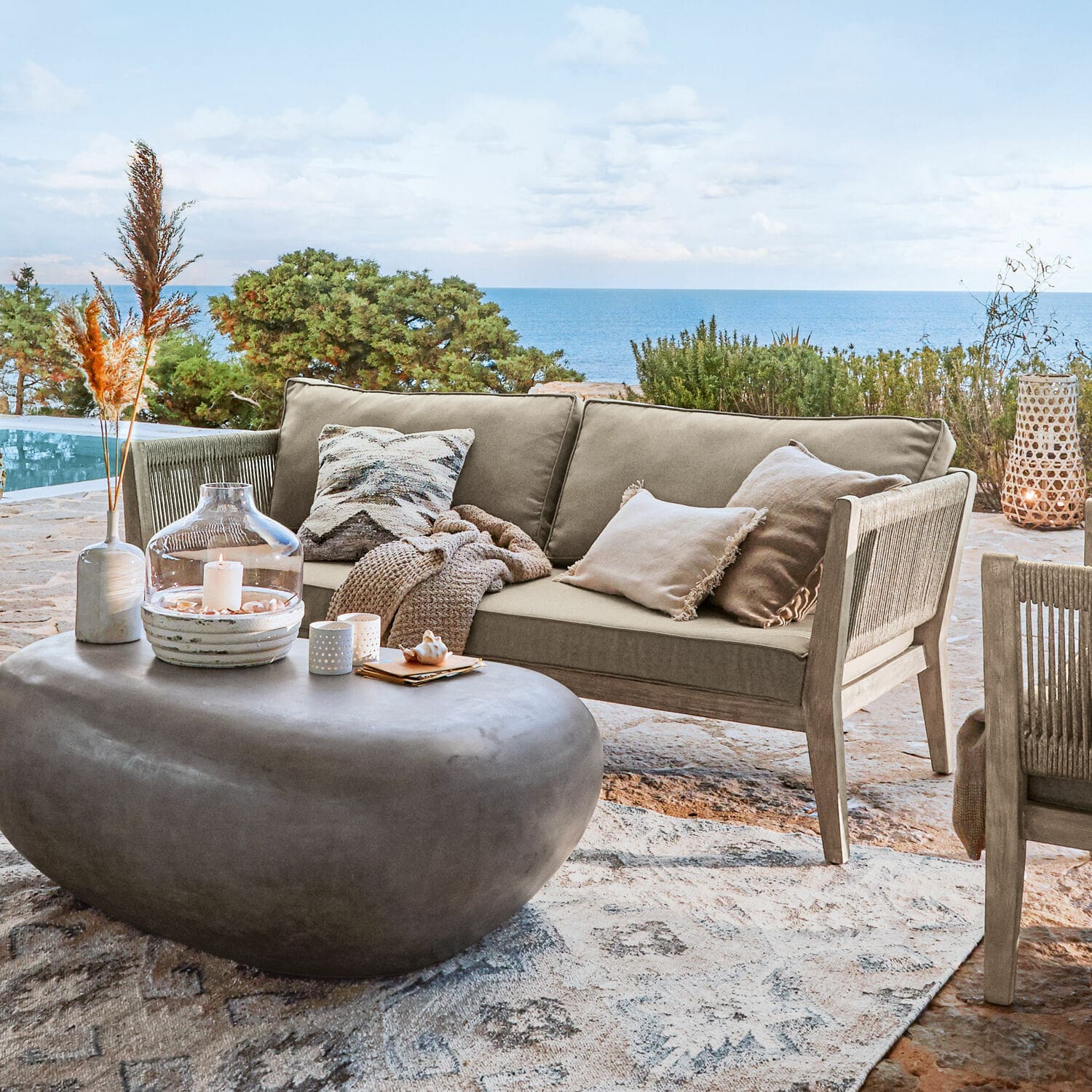 Sofa Biarritz Beiges Outdoor-Sofa aus Holz und Stoff auf der Terrasse mit Meerblick, moderner Steintisch