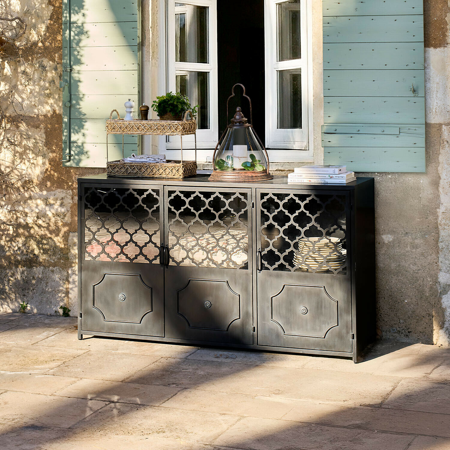 Sideboard Astralon Schwarzes Metall-Sideboard mit filigranen Türen auf Terrasse vor Fenster mit grünen Fensterläden